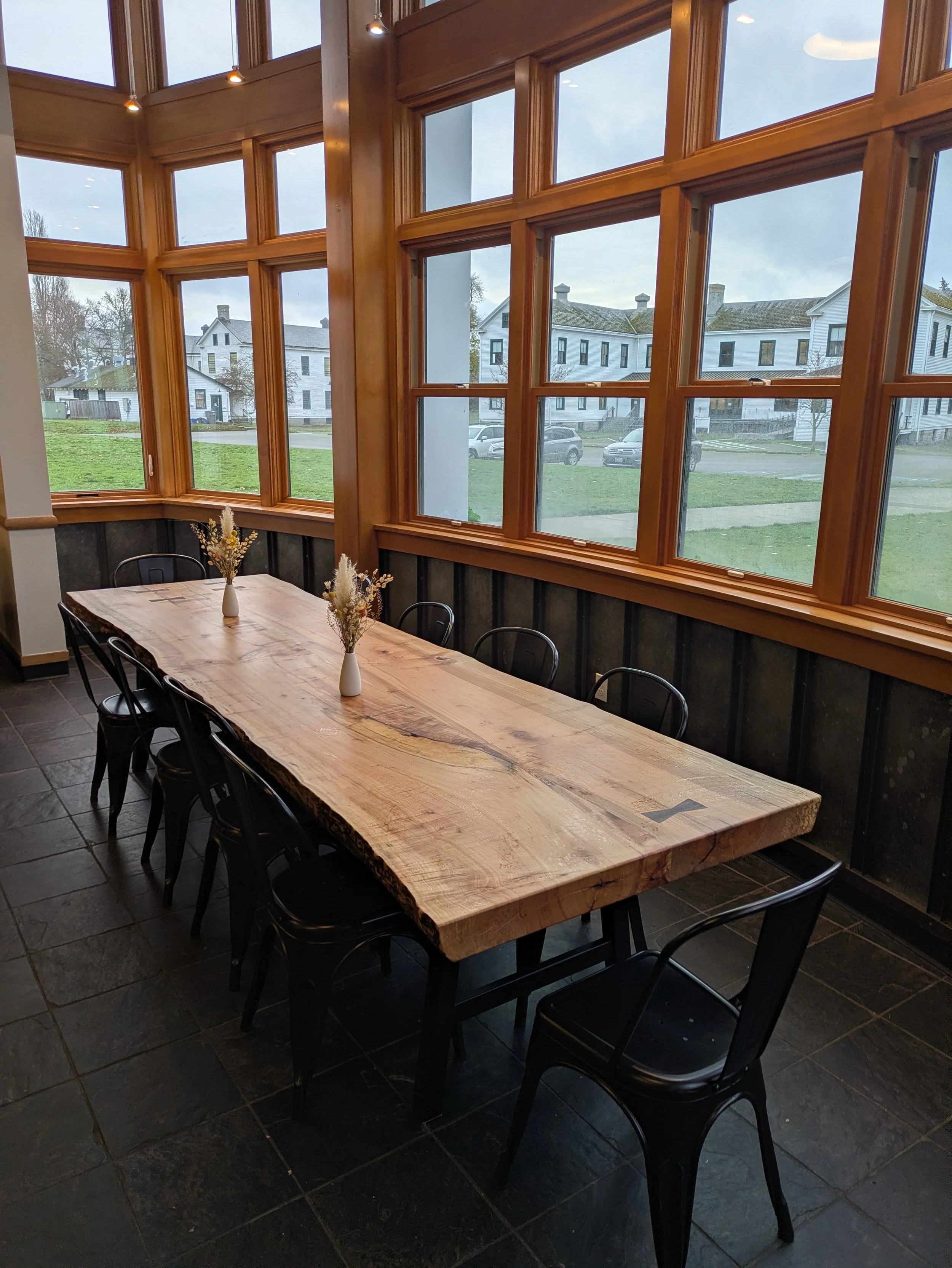 Large handcrafted maple slab dining table with black steel chairs, PNW craftsman interior