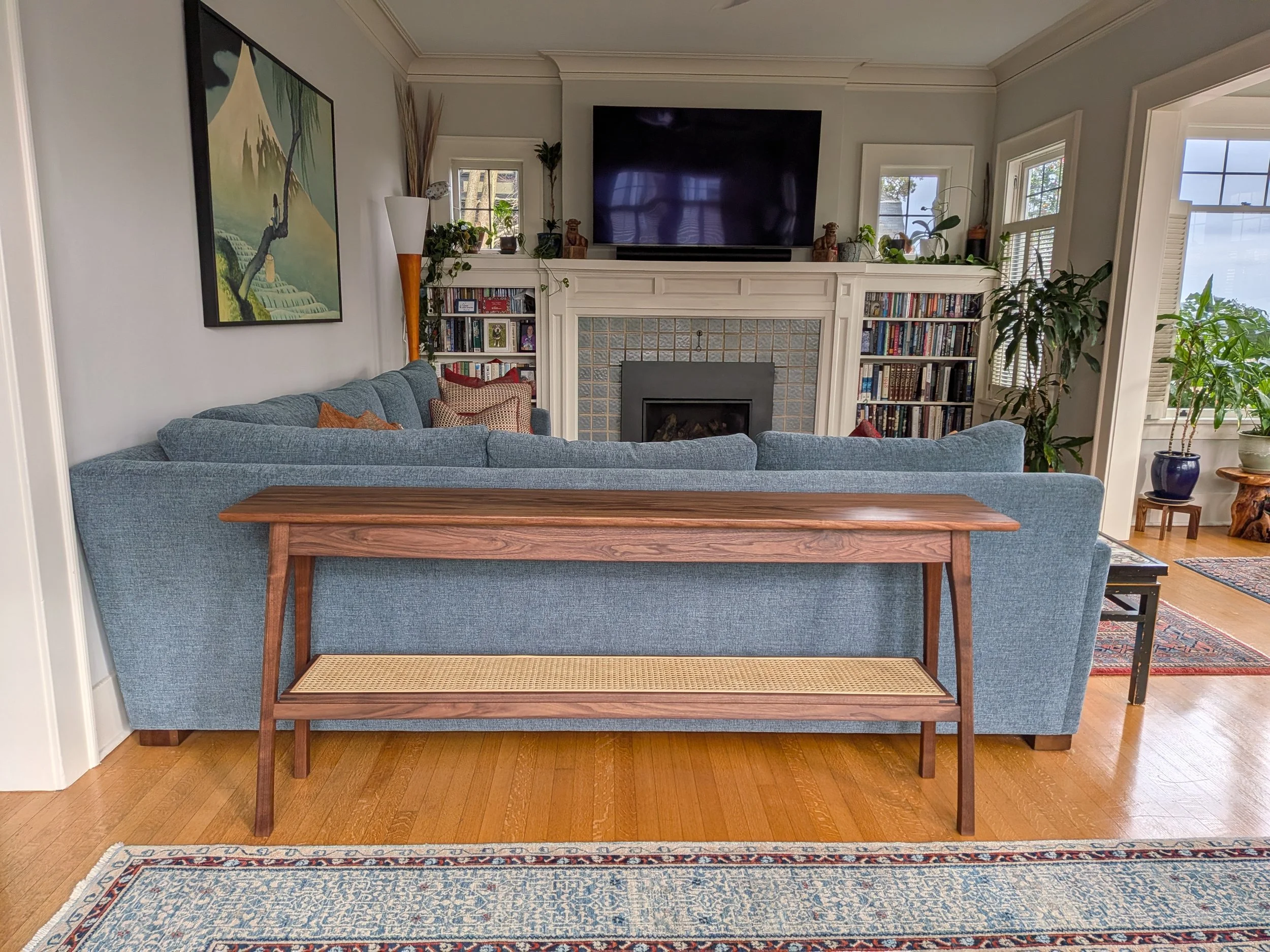 Solid walnut sofa table with cane shelf, front view in modern living room