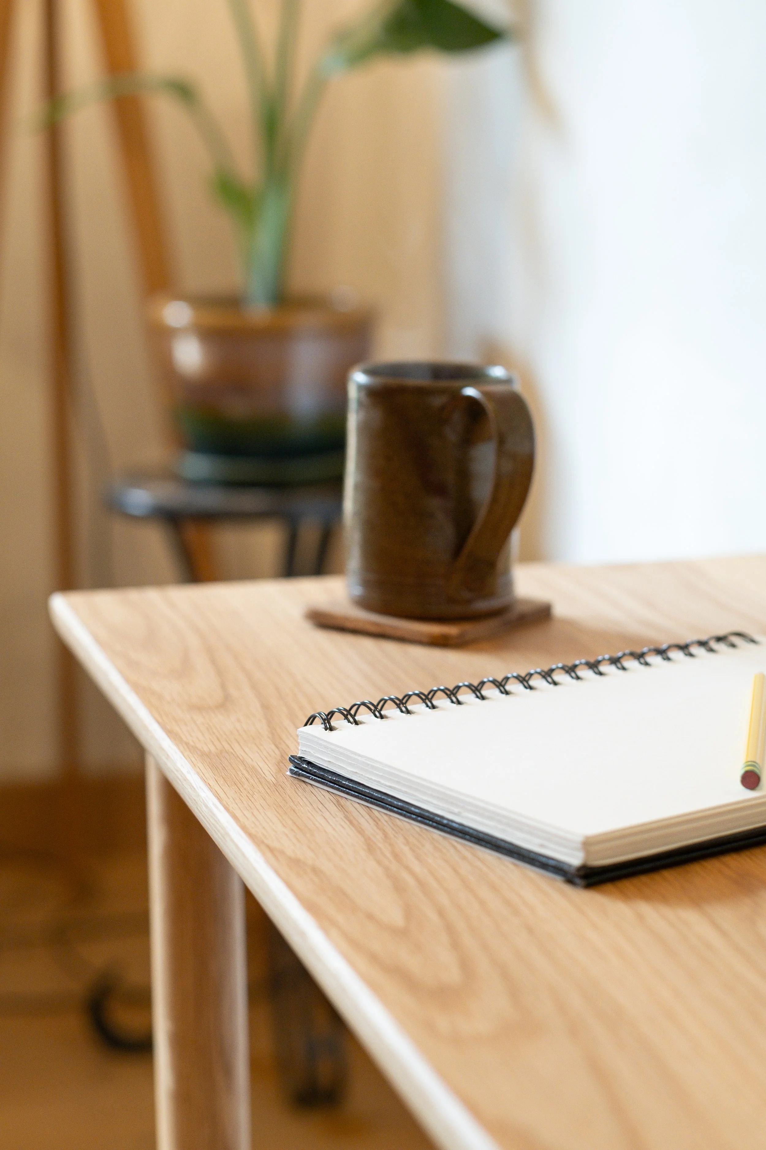Wren Desk tabletop corner detail with notebook and mug, solid white oak grain