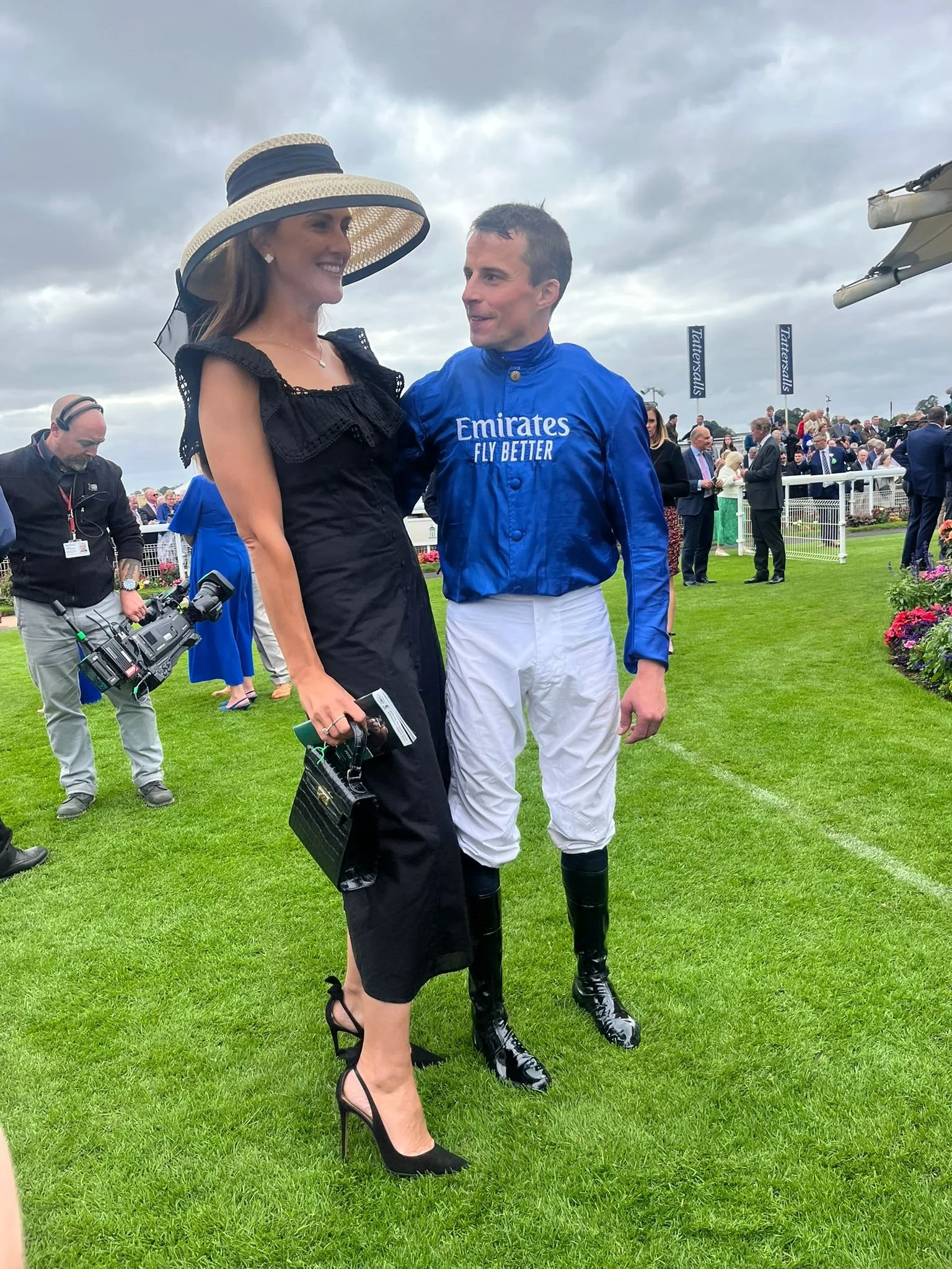 Jane Buick in a large sisal straw 'dior' down brim hat with her winning jockey husband William Buick