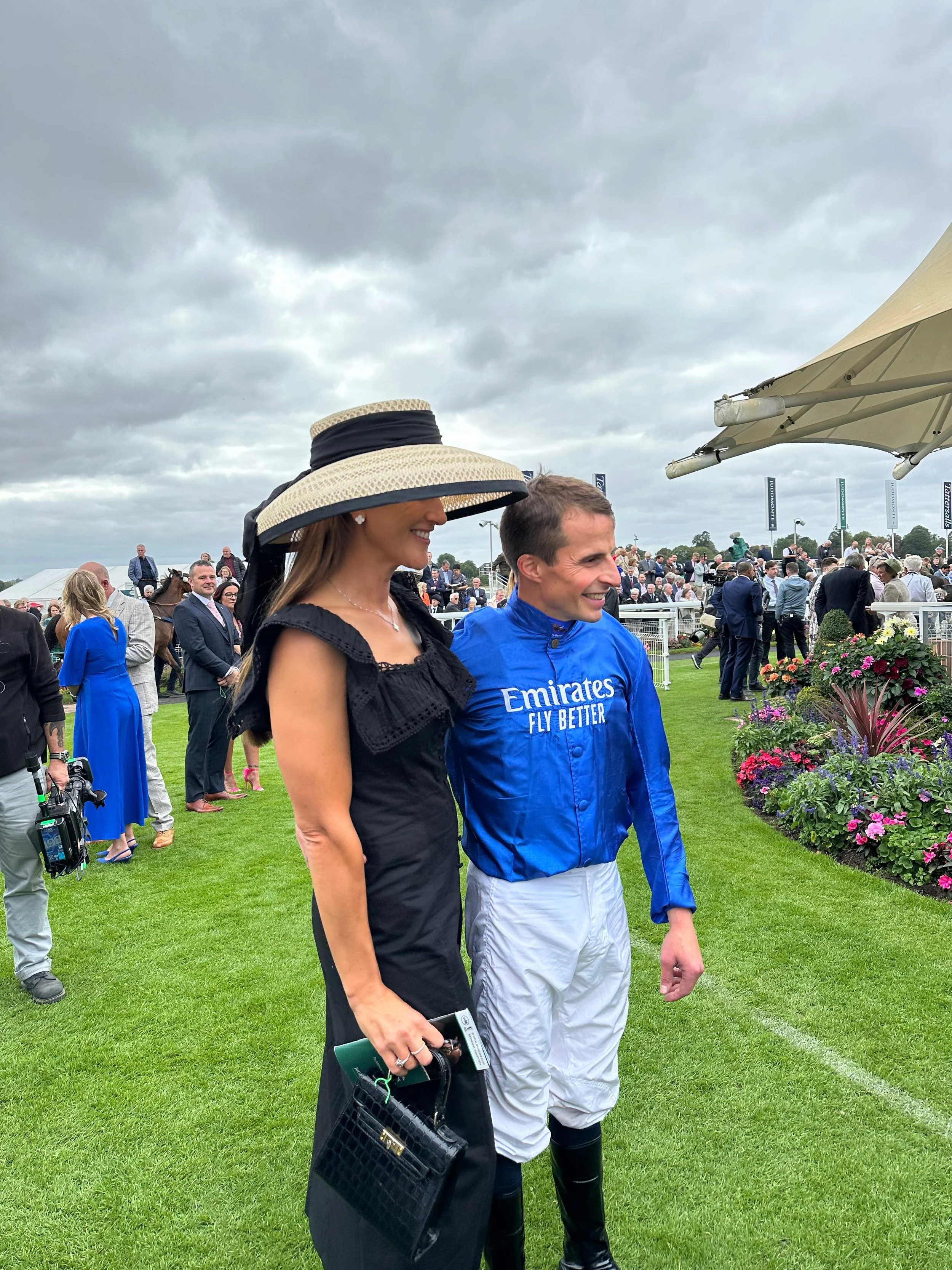 Jane Buick in a large sisal straw 'dior' down brim hat with her winning jockey husband William Buick