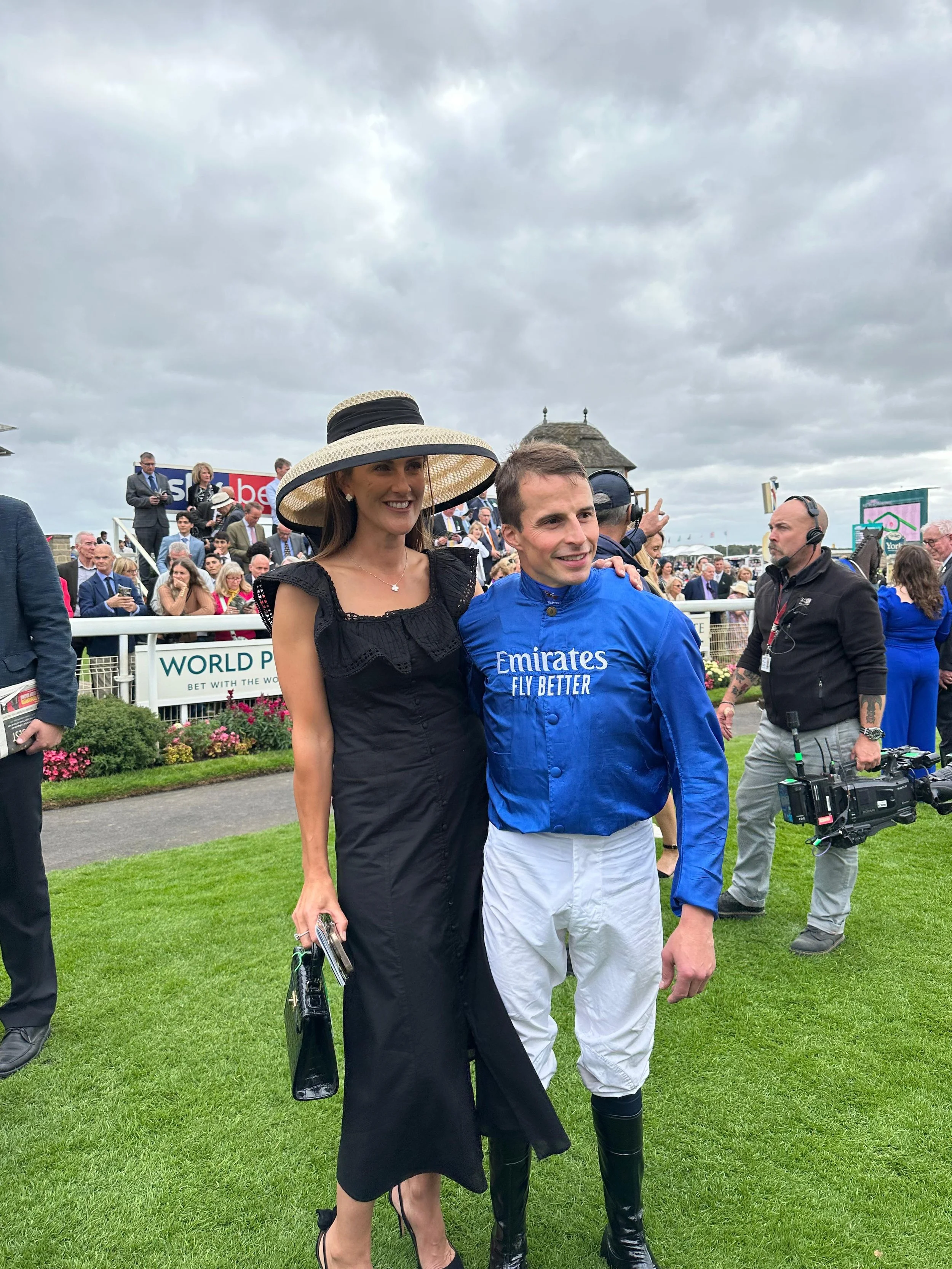 Jane Buick in a large sisal straw 'dior' down brim hat with her winning jockey husband William Buick