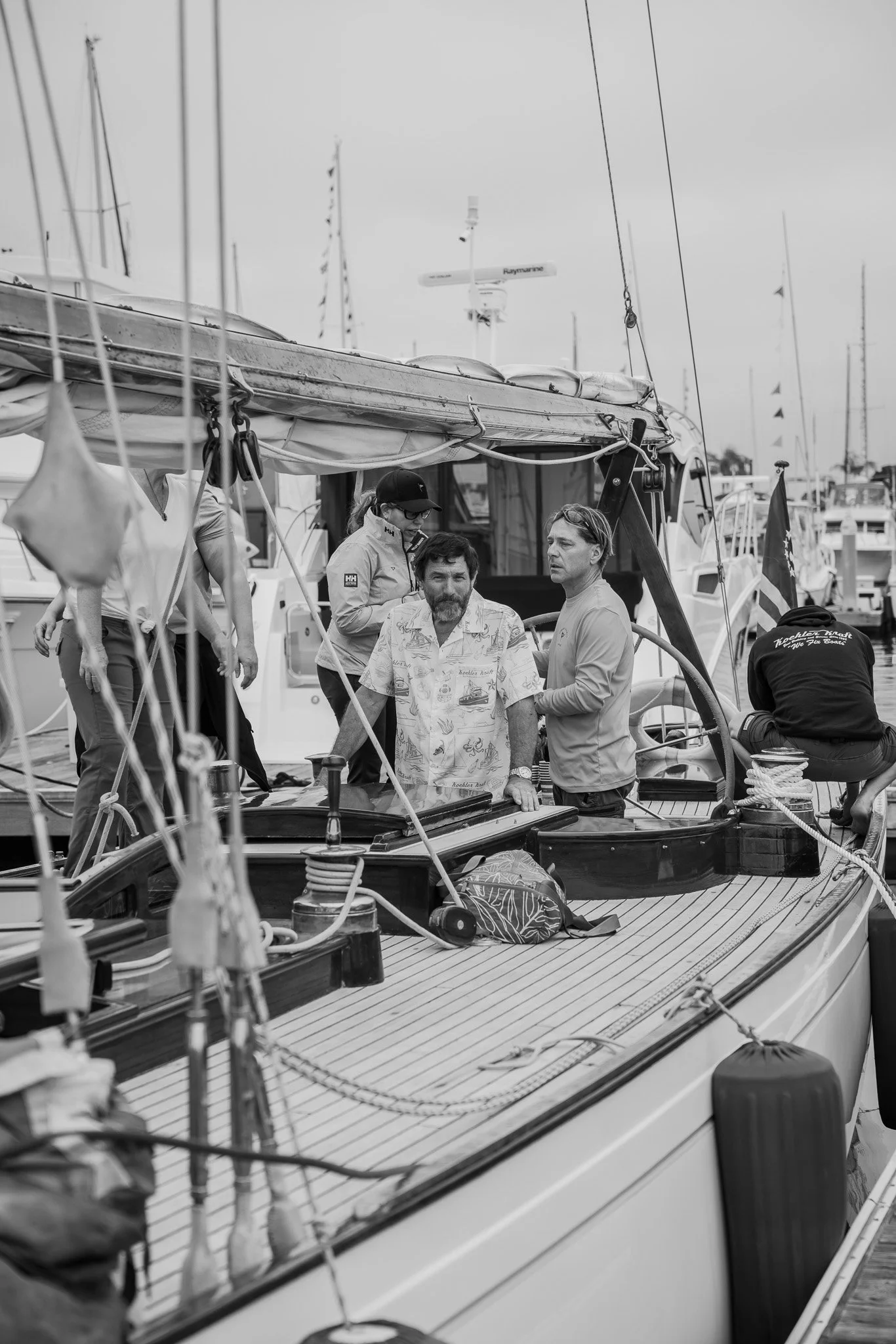 People on a sailboat docked at a marina.
