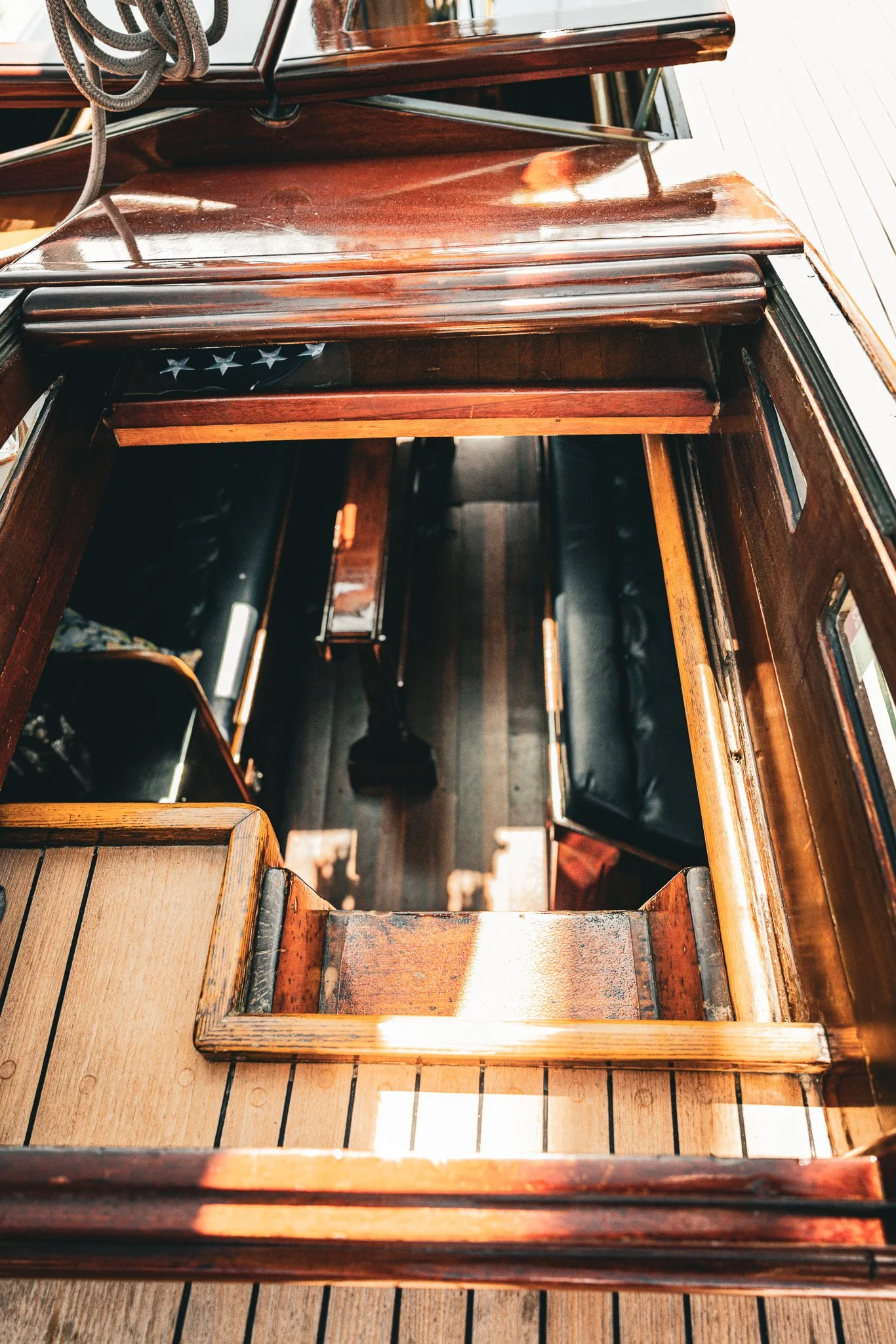 View from the top of a wooden boat interior showing the deck, seating, and part of a flag with white stars on a blue background.