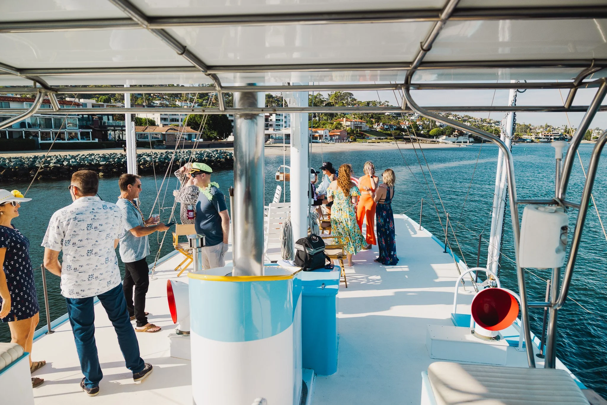 People enjoying a boat cruise on a sunny day with a view of the shoreline and houses.