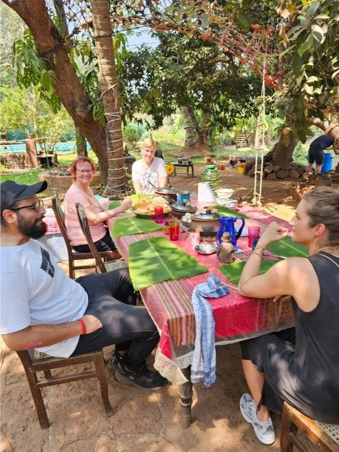 Farm-to-table workshop at The Art Farm, Goa  - guests sharing a fresh, organic community meal under trees, celebrating sustainable local food in India.