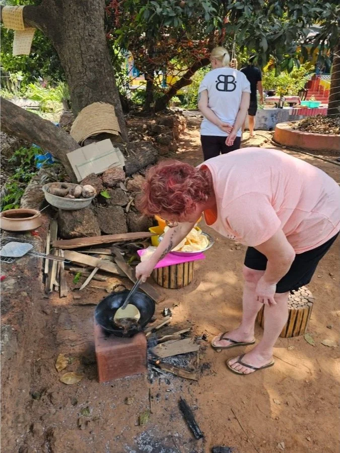 Guest learning traditional wood-fire cooking at The Art Farm, Goa - hands-on sustainable food workshop in rural India.