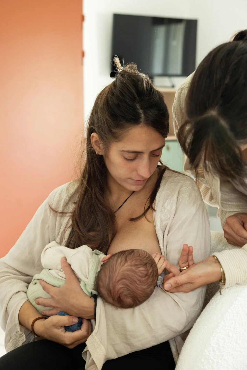 Une femme allaite un bébé dans un intérieur domestique.