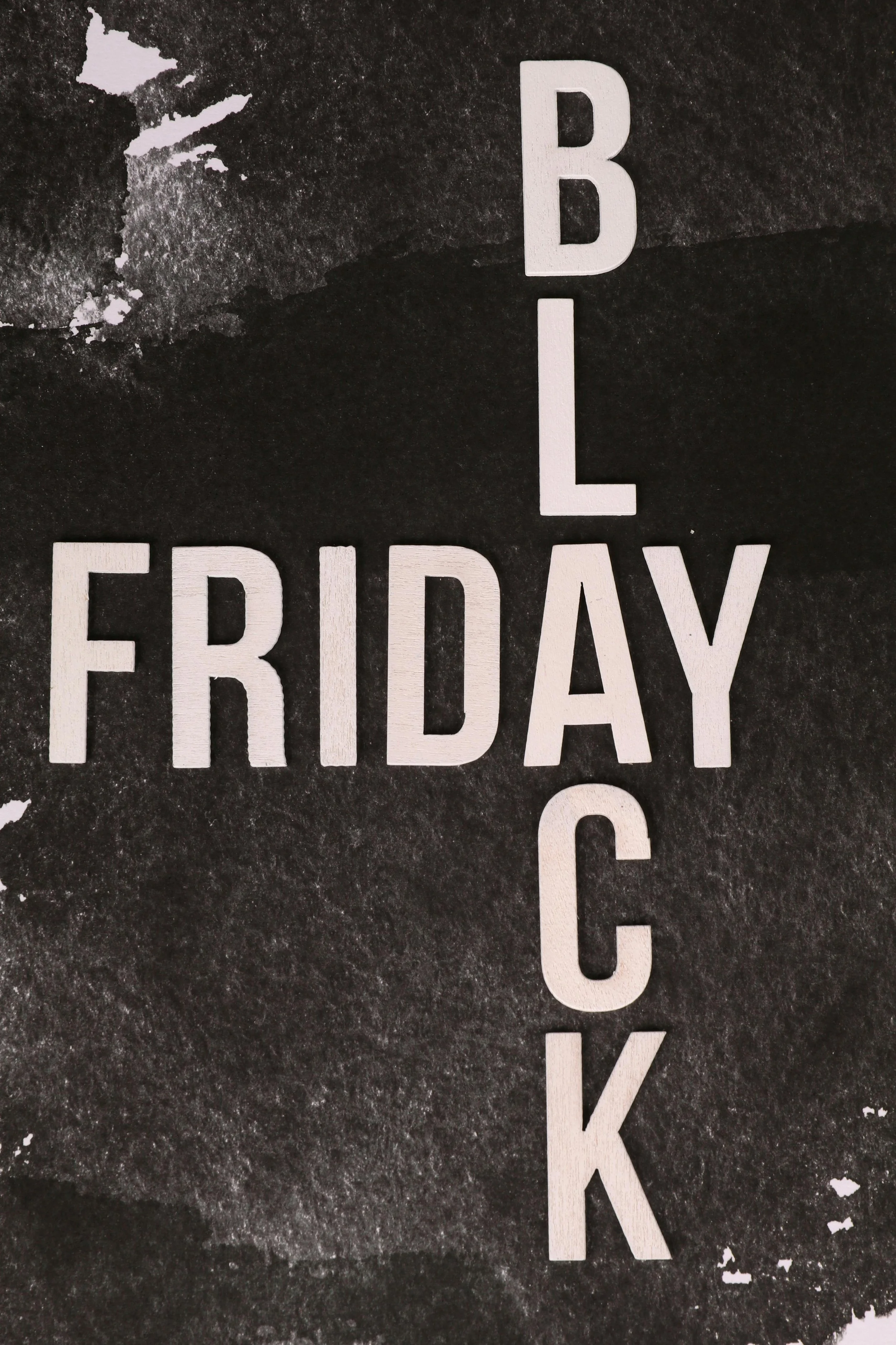White wooden letters spelling 'BLACK FRIDAY' arranged vertically on a black textured background.