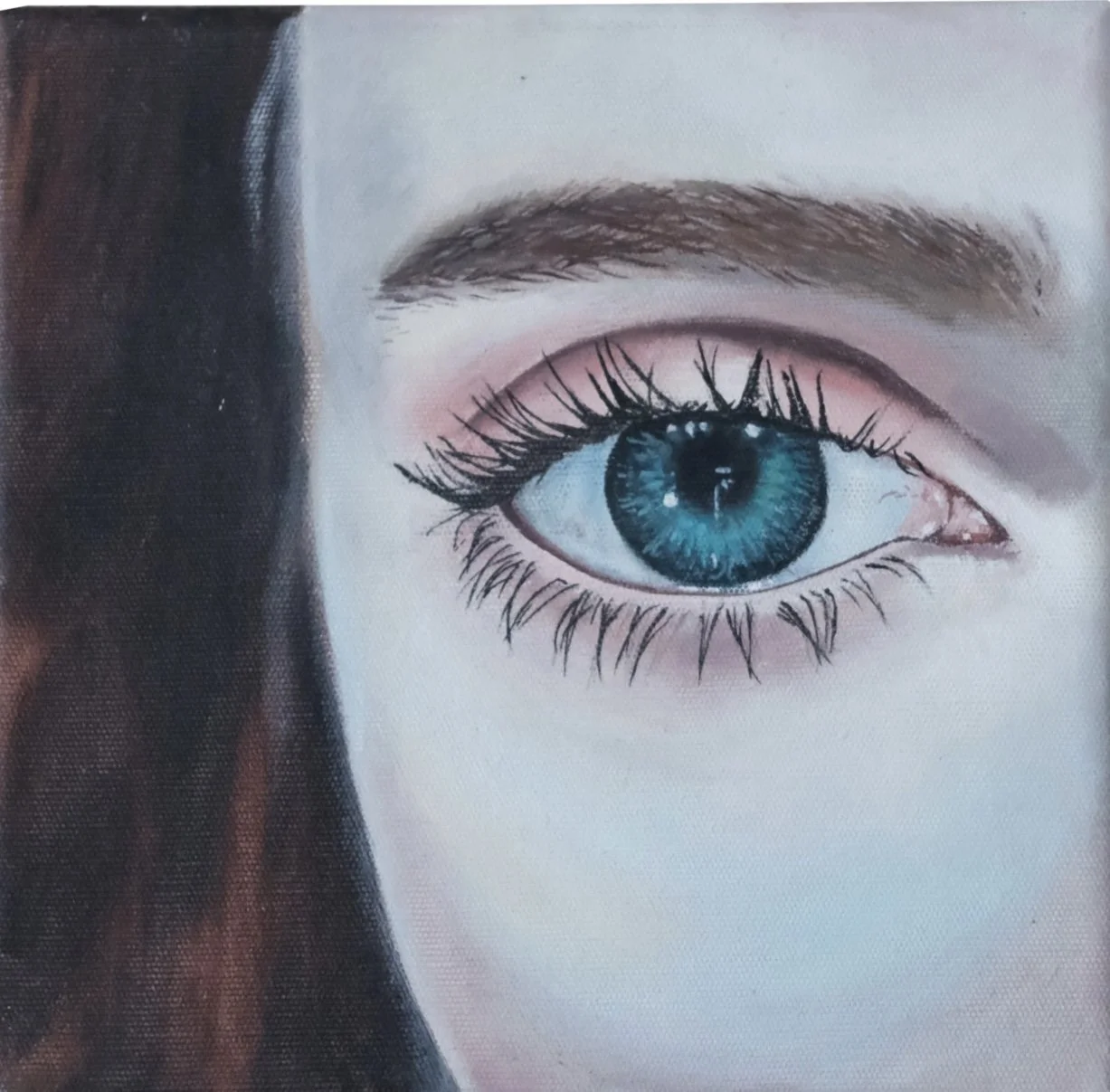 Close-up of a person's eye with bright blue iris, surrounded by detailed eyelashes and well-defined eyebrows, partially obscured by dark hair on the left.