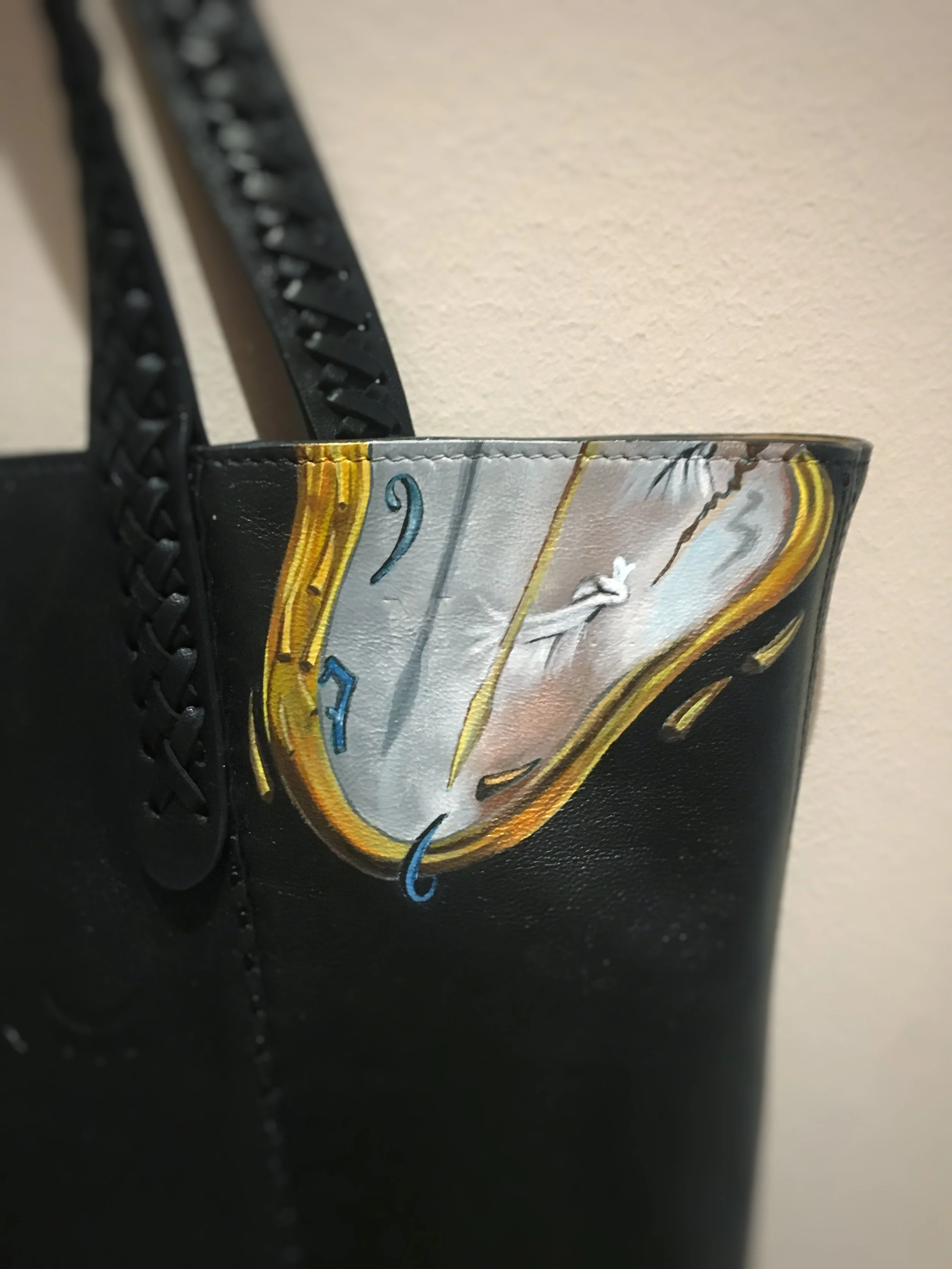 Close-up of a black shoe with a mural of a clock painted near the top edge of the shoe.