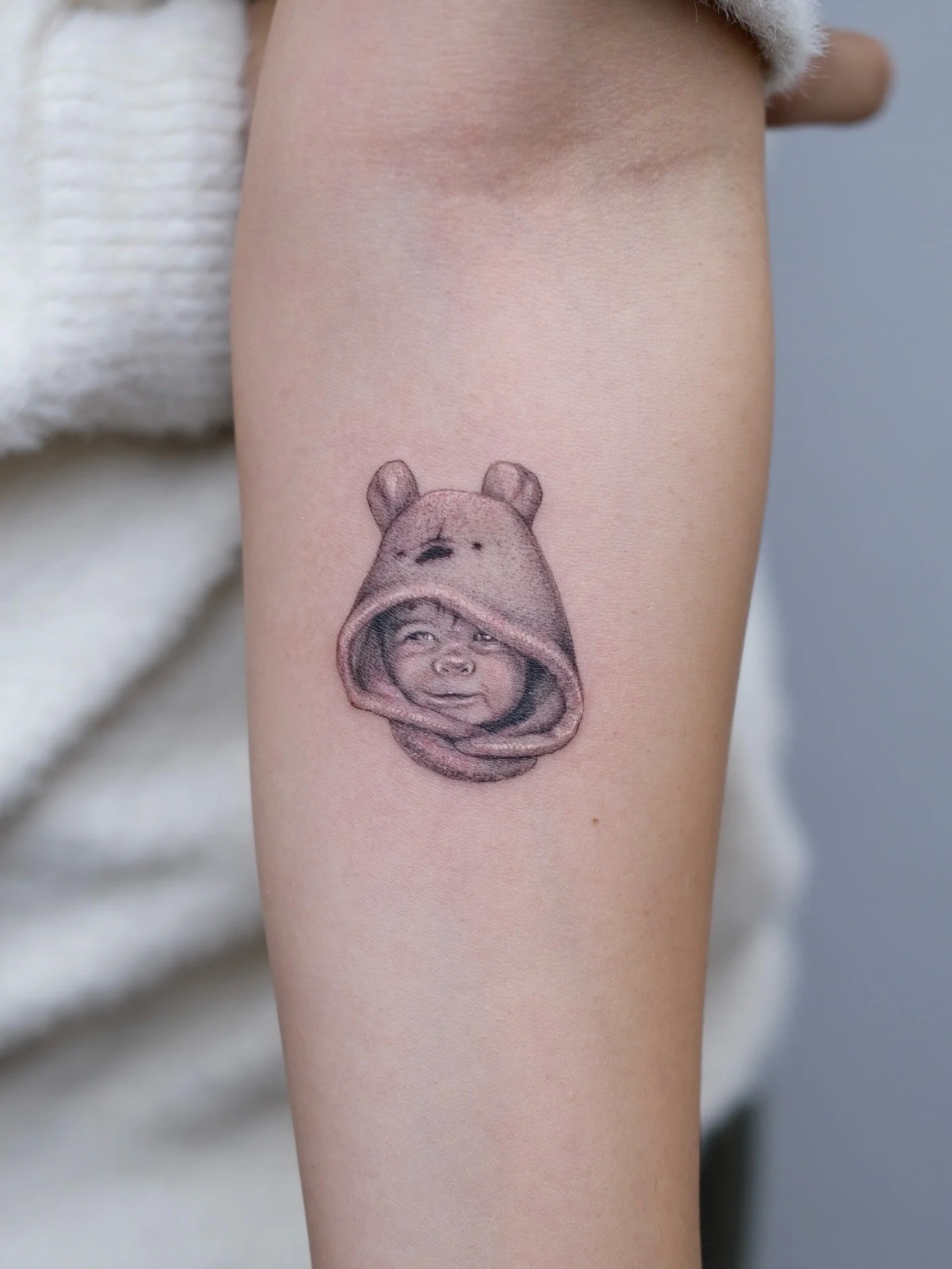 Tattoo of a child wearing a hoodie on a person's arm.