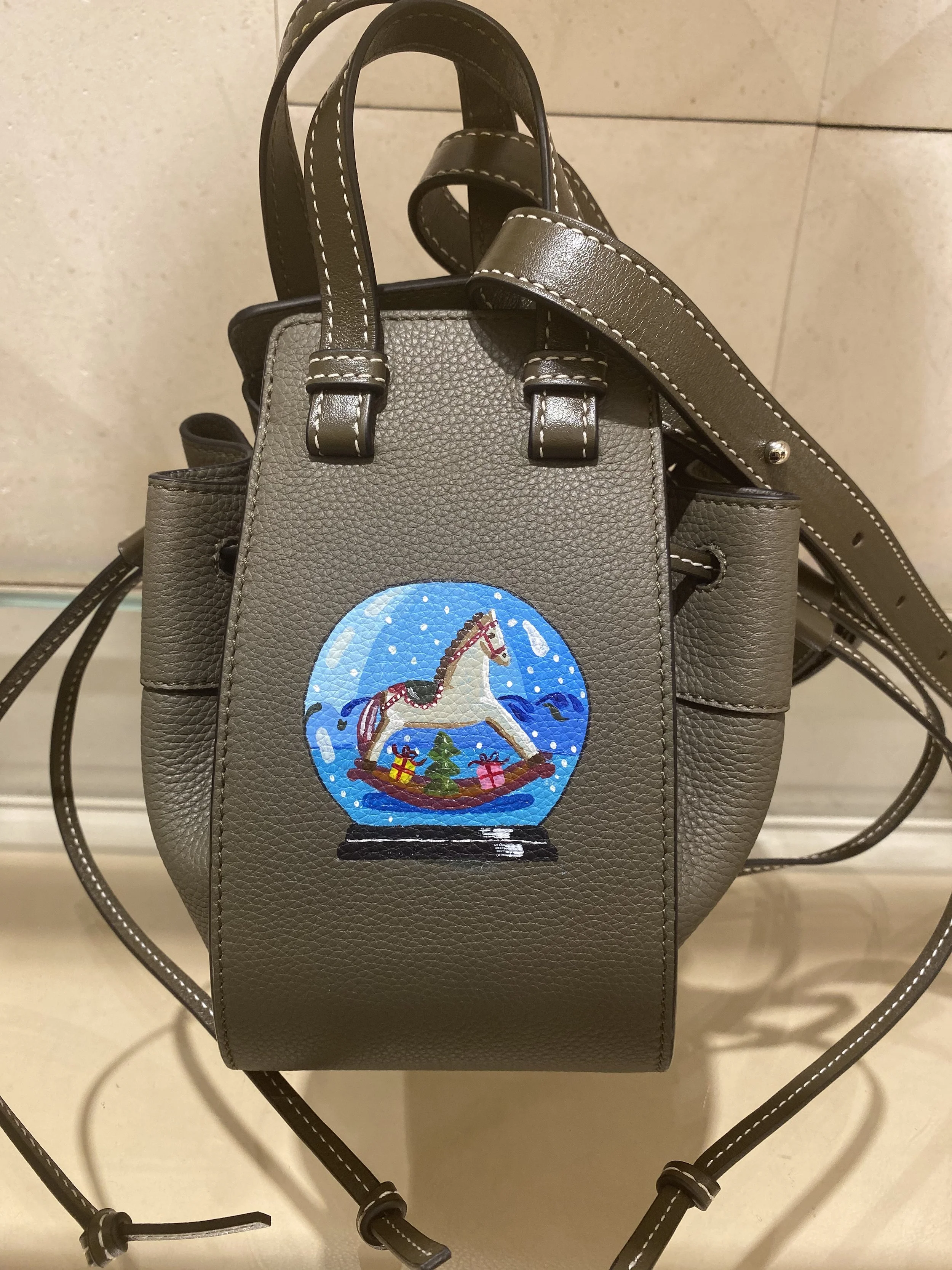 Gray handbag with a colorful snow globe patch featuring a white horse, Christmas presents, and a pine tree.