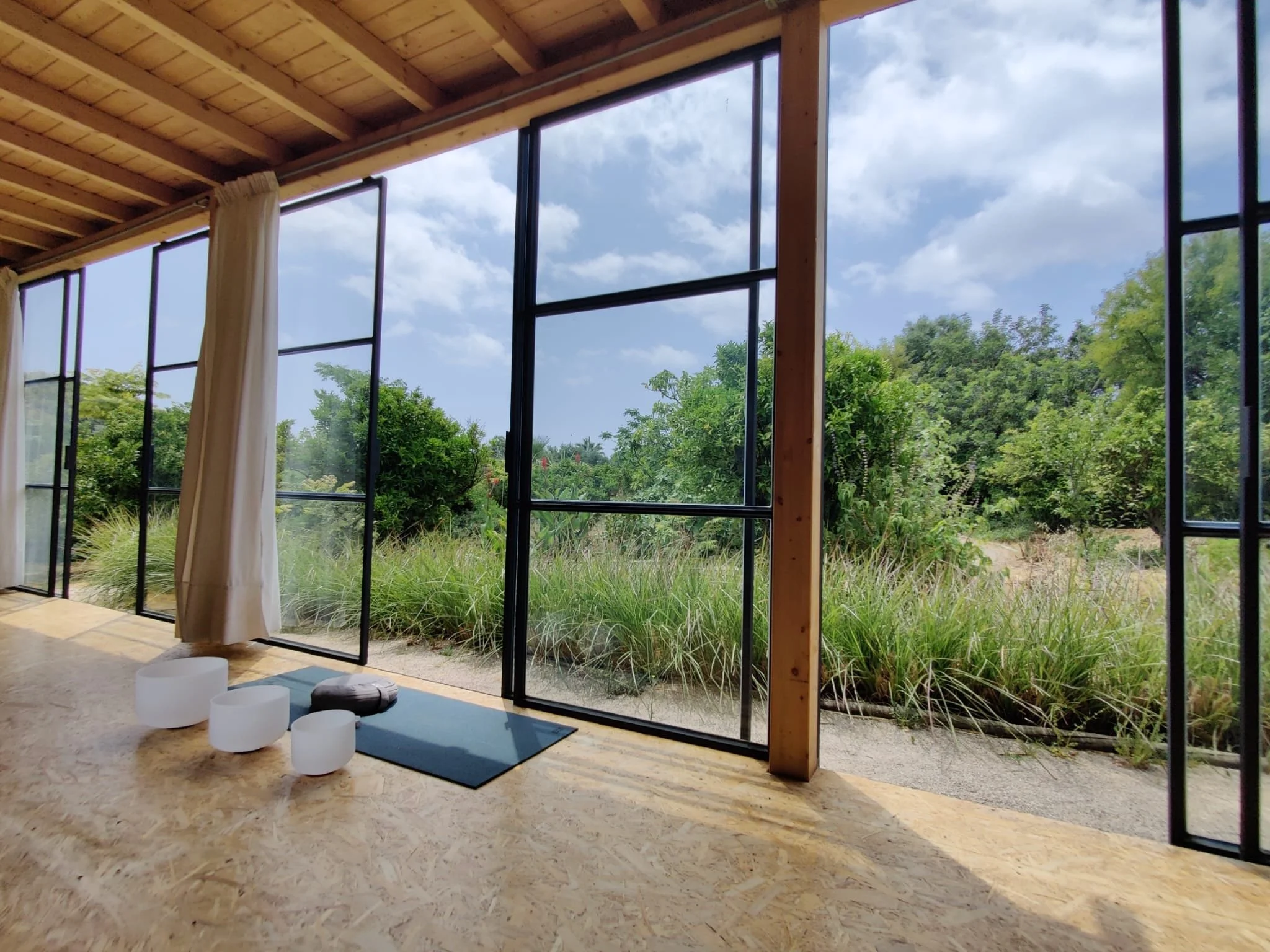 Breathwork space with sound bowls in a calm, light-filled studio surrounded by nature.