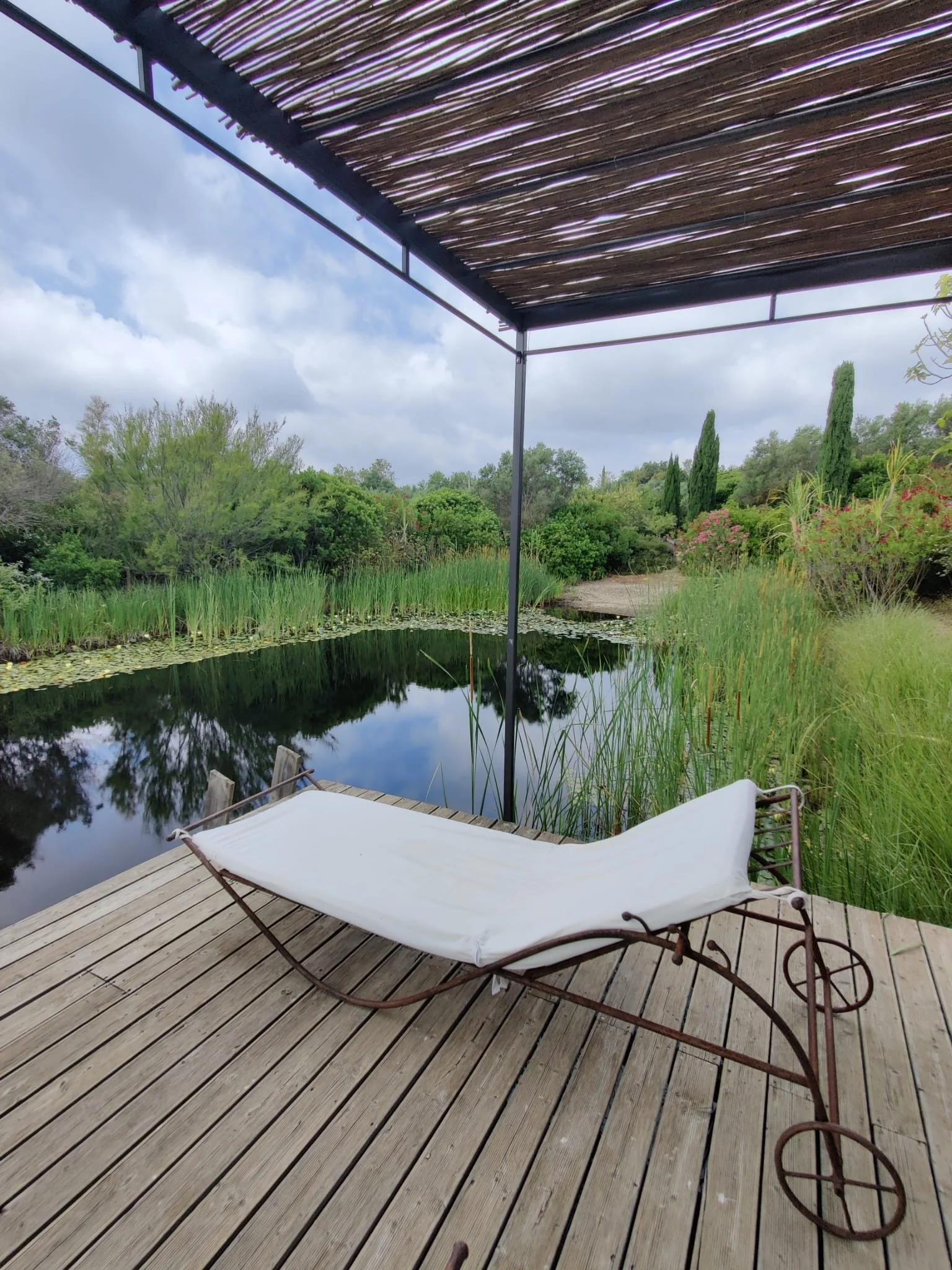Hammock beside the pond on a wooden deck, symbolising peaceful rest during the retreat.