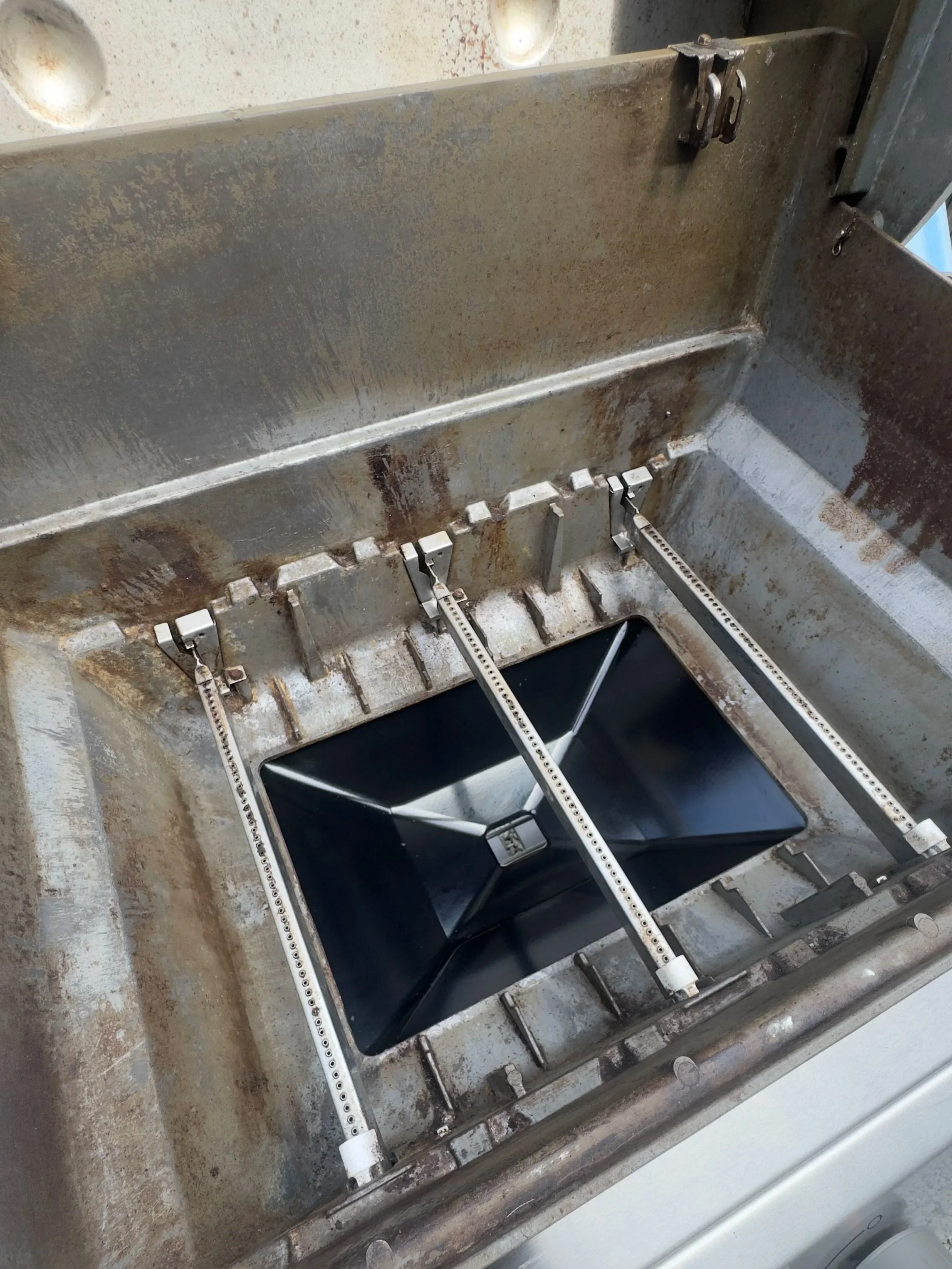 View inside an industrial machine with a black component and metal parts, showing signs of rust and wear.