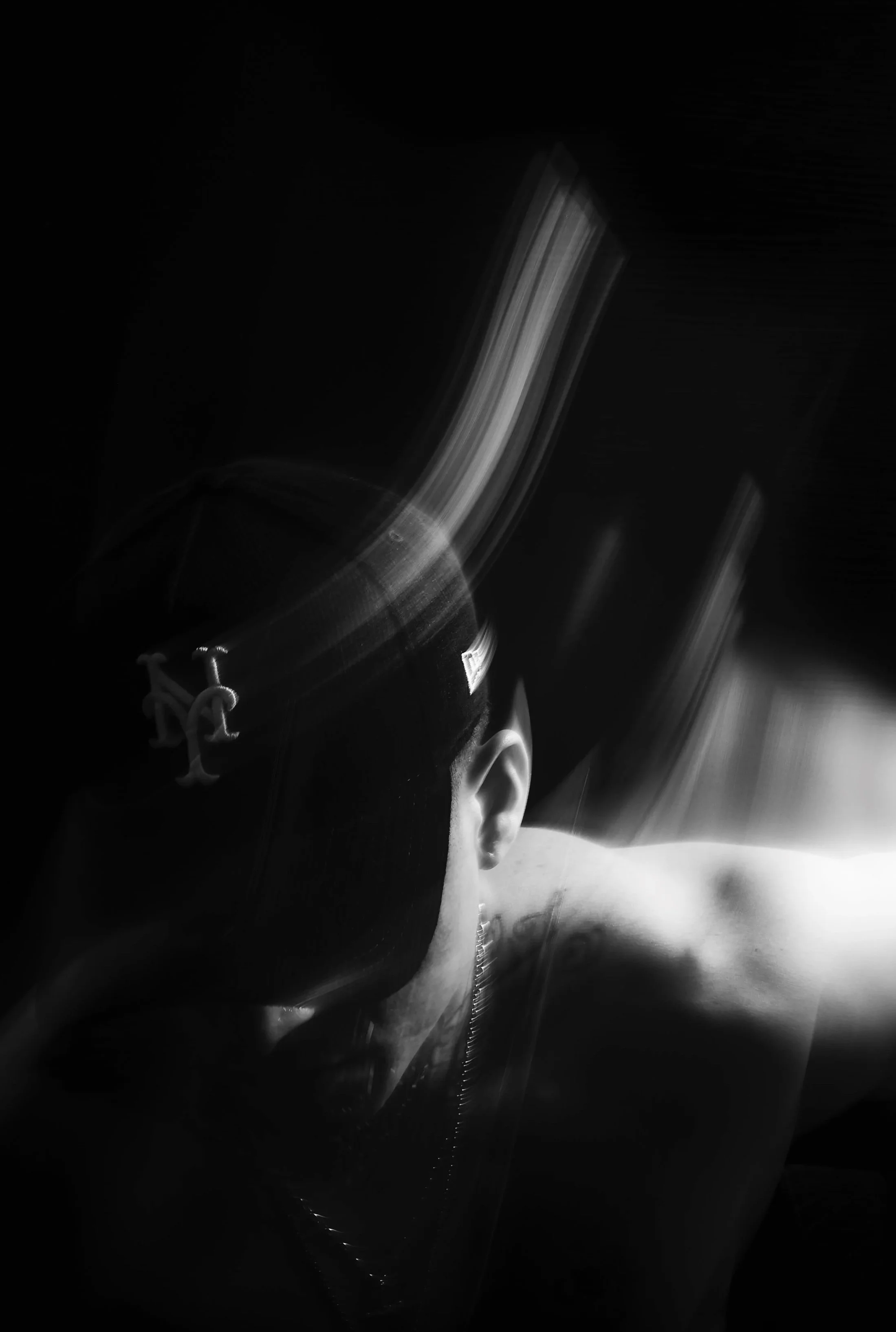 Auto-Portrait en noir et blanc du photographe portant une casquette, avec un fond sombre, effets de mouvement ou de flou. autoportrait.