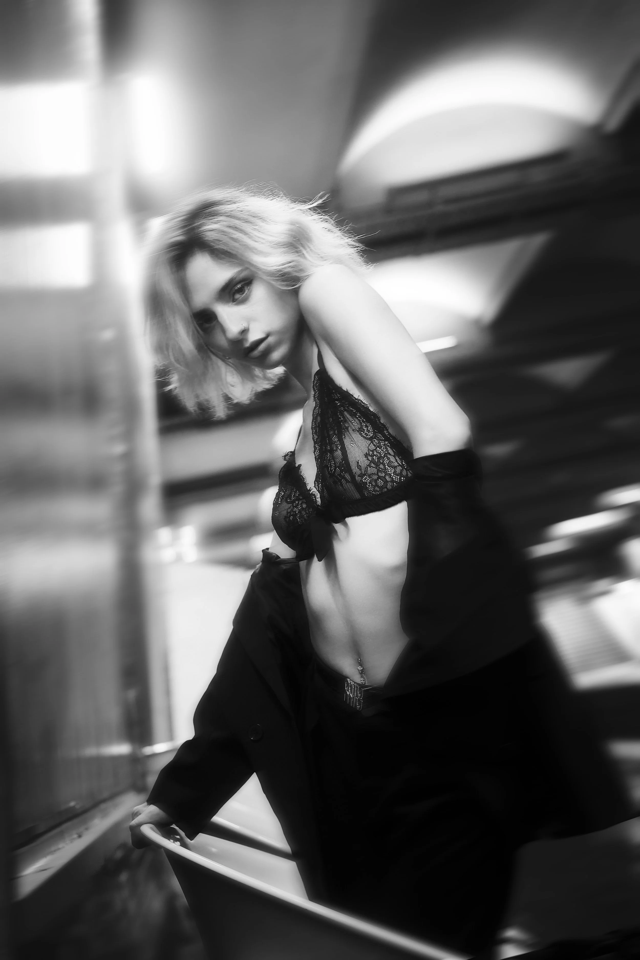 Photo pour séance Portrait Intimiste. Une jeune femme en lingerie noire, posant dans un environnement sombre et urbain, photo en noir et blanc.