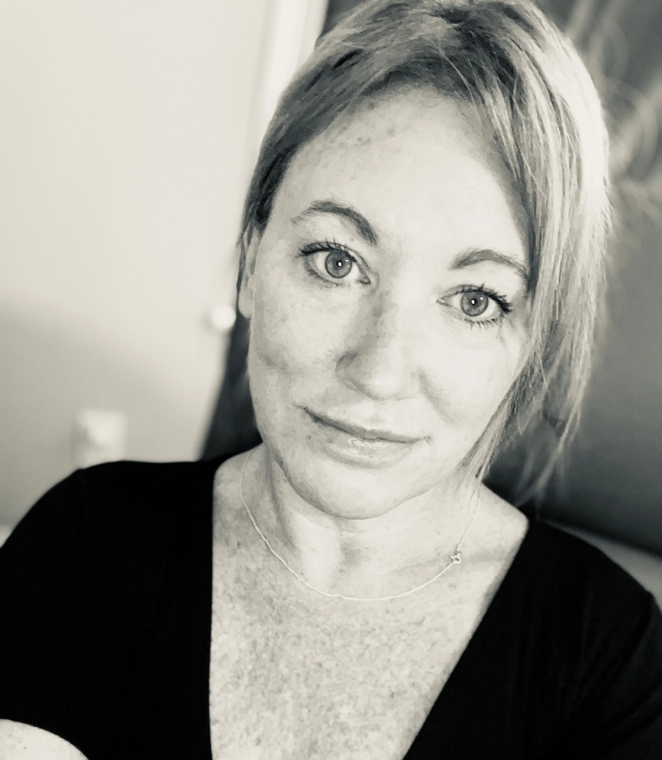 Black and white close-up photo of a woman with short hair and light-colored eyes smiling slightly.