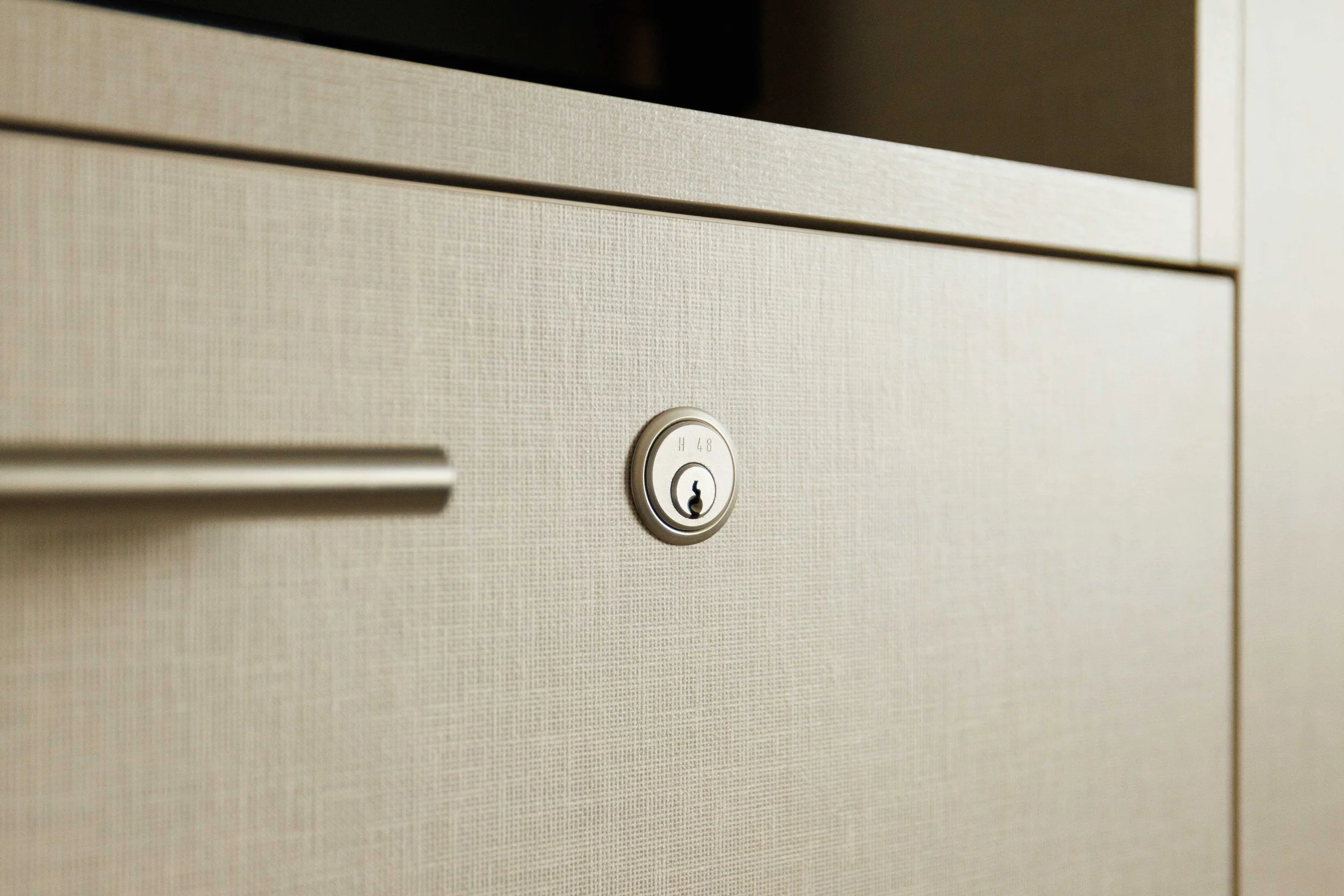 Nahaufnahme eines beigefarbigen Schranks mit einer Metallklinke und einem Schlüsselloch