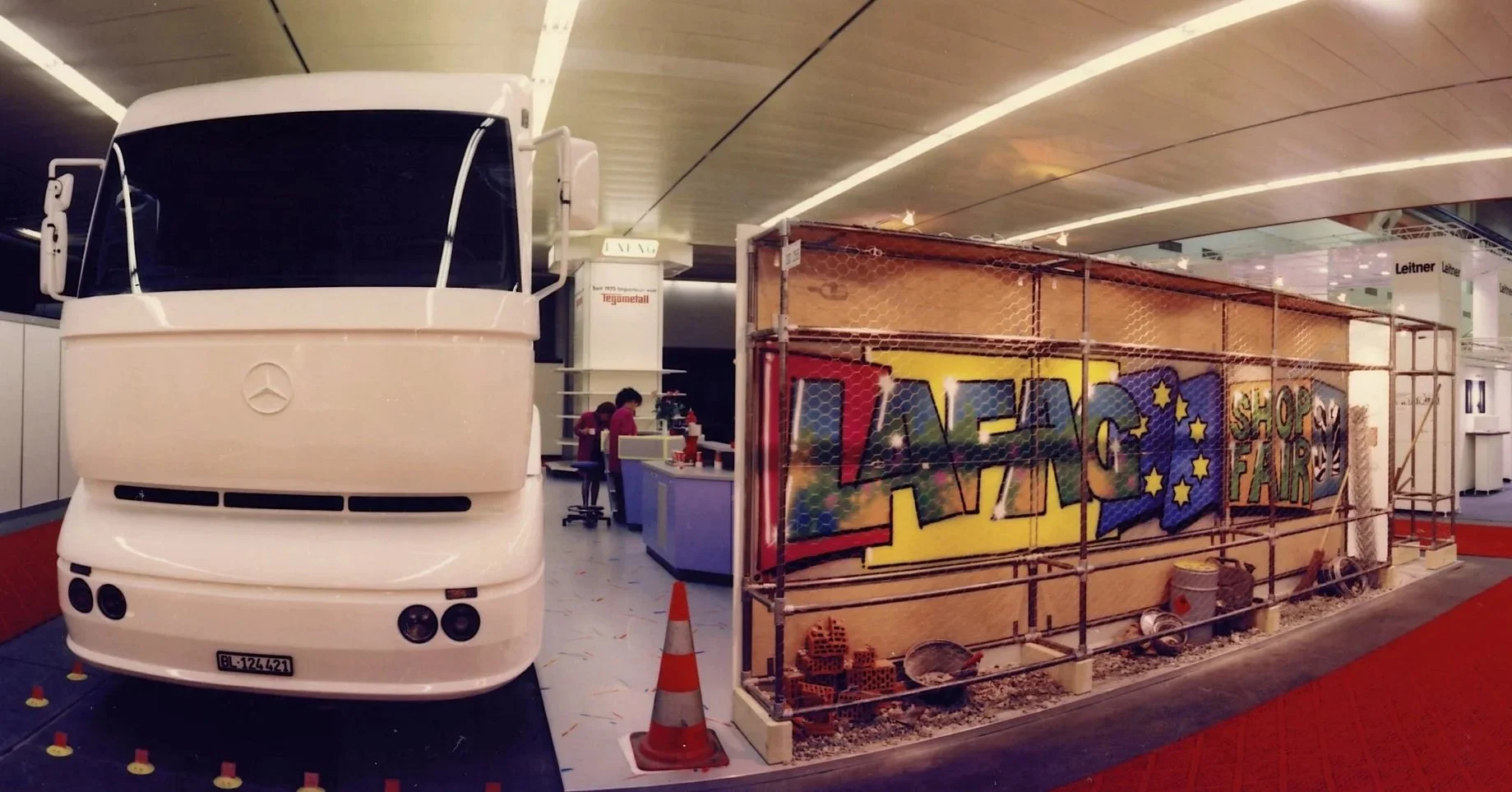 Ein rollender Bus steht neben einem Spielbereich mit Graffiti-Grafik, umgeben von Baugerüsten und Sicherheitsabsperrungen.