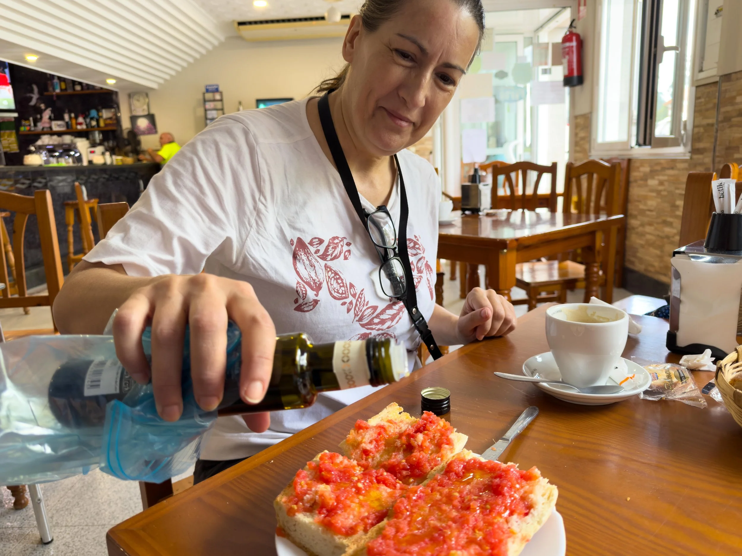 Olga dressing up the tomato toast with her always present bottle of olive oil 