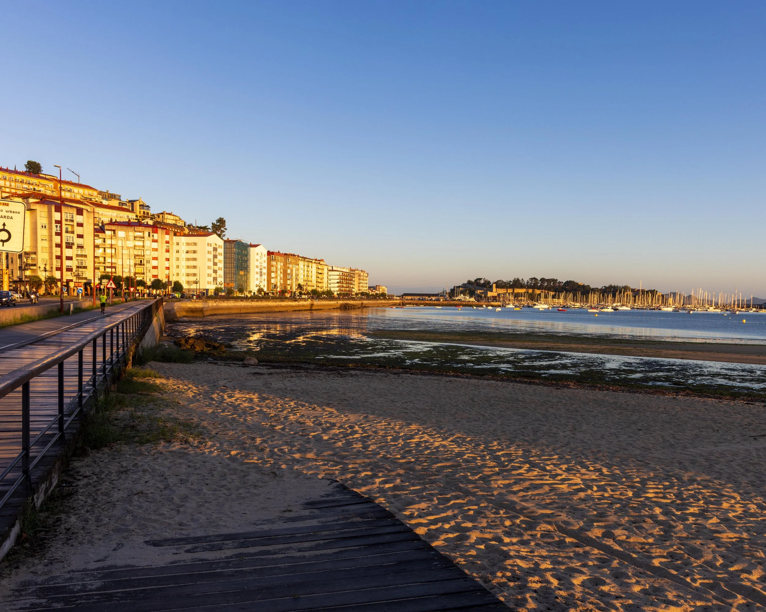 Beautiful sunrise lights up the buildings along the harbor in Baiona