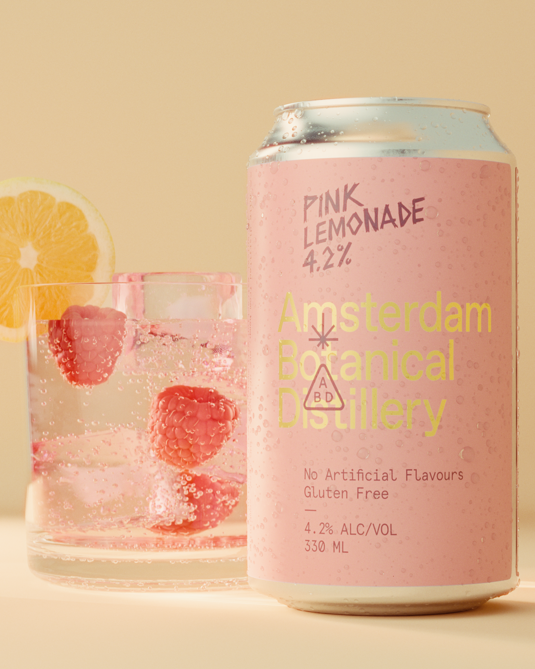 A can of pink lemonade alcohol drink with bubbles and condensation, with a partial view of a glass containing raspberries, and lemon slices, against a neutral background.