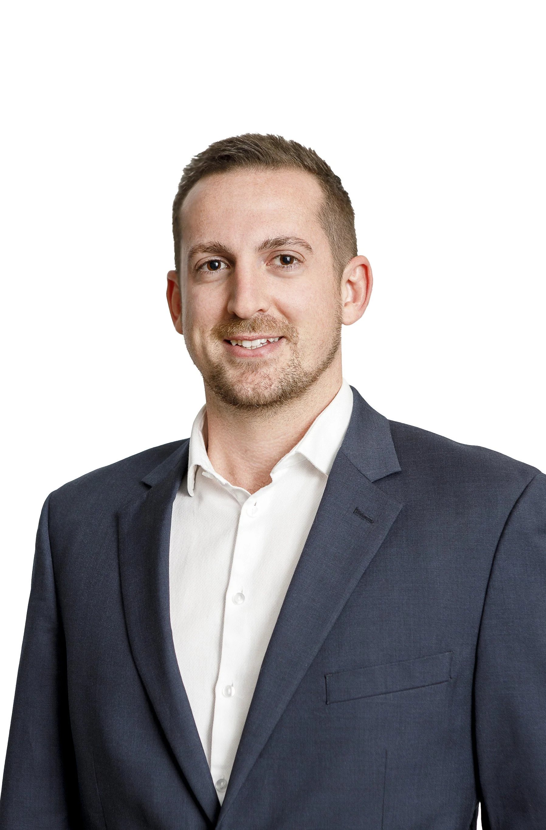 Portrait of a smiling man in a navy blue blazer and white shirt standing in front of a white background.
