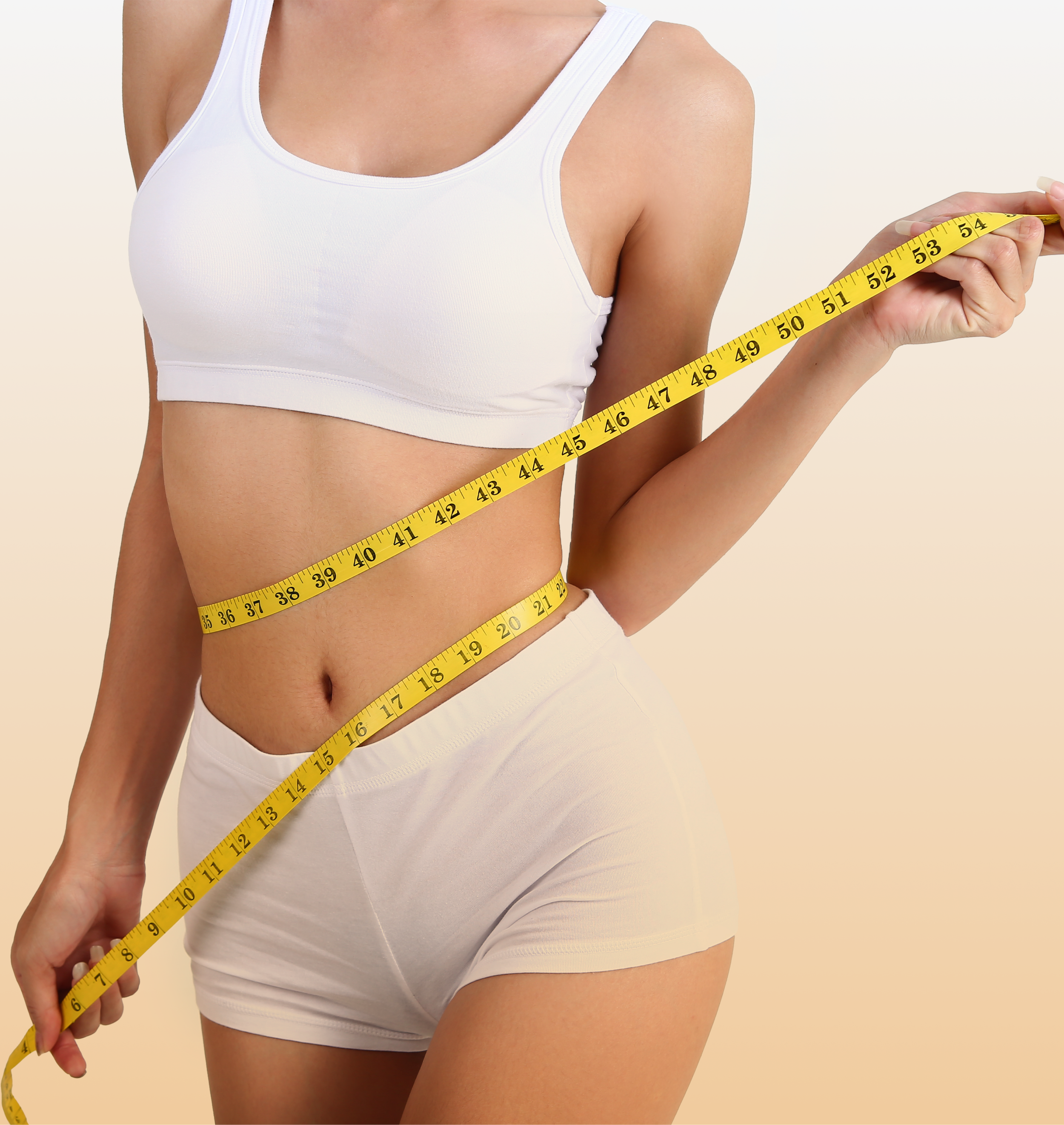 Woman with toned body measuring her waist with tape