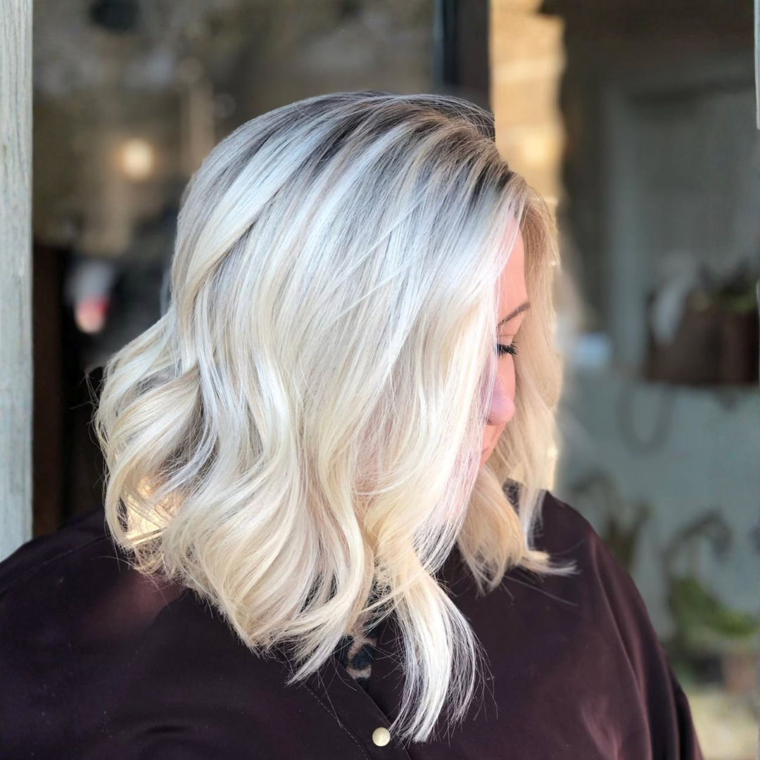 Side view of a woman with shoulder-length platinum blonde hair styled in soft waves.