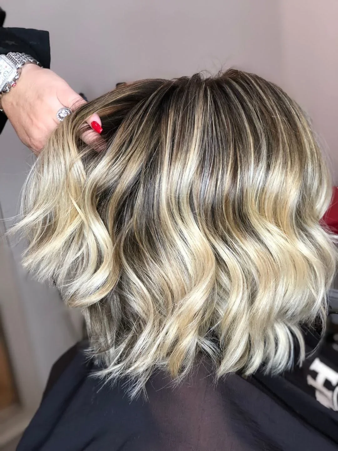 Close-up of styled blond hair with dark roots and loose waves, a good example of blonde balayage.