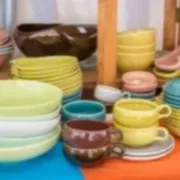 Stacked colorful ceramic dishes and bowls on a shelf.
