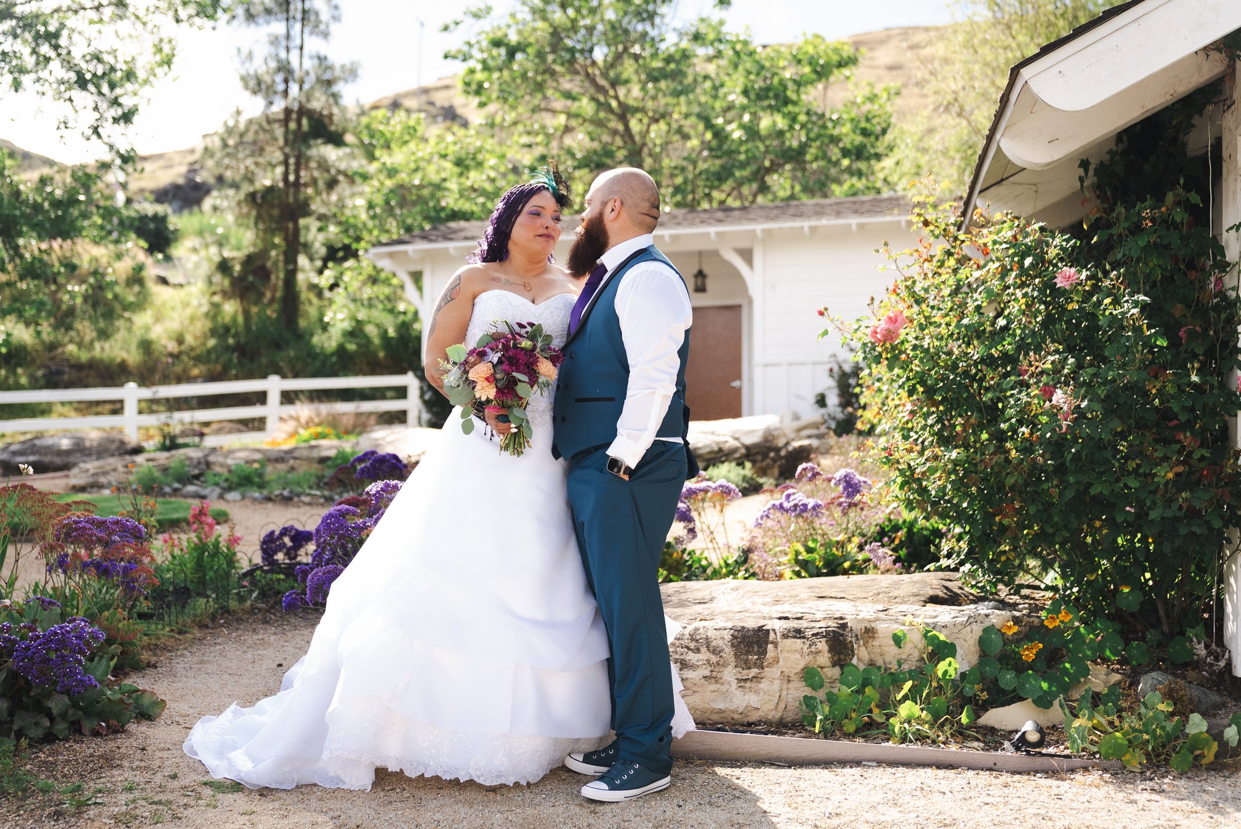 a bride and groom stare at each other outside in a floral garden