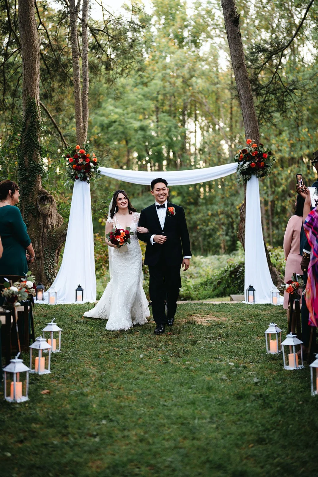 A bride and groom walk down the aisle after their ceremony in the woods