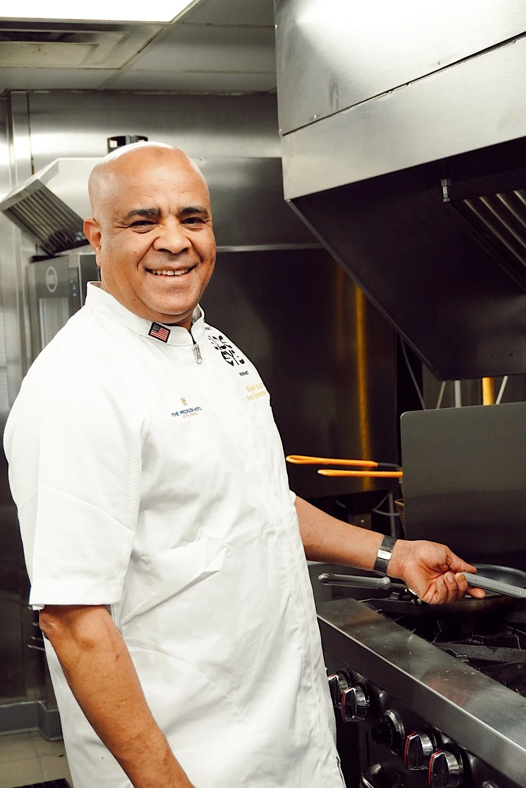 Chef cooking in the kitchen at Side Eye restaurant inside The Mecklen Hotel, standing beside a stovetop in a professional culinary workspace.