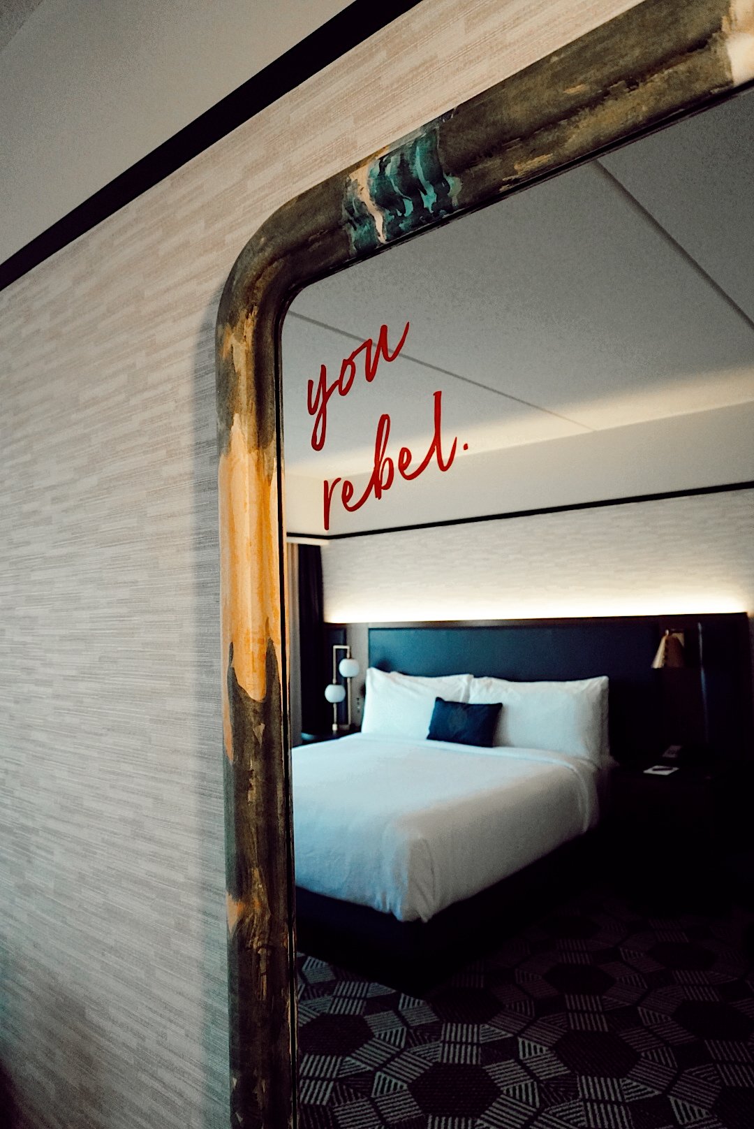 Floor length mirror in guest room with "You Rebel" written on the upper right corner.