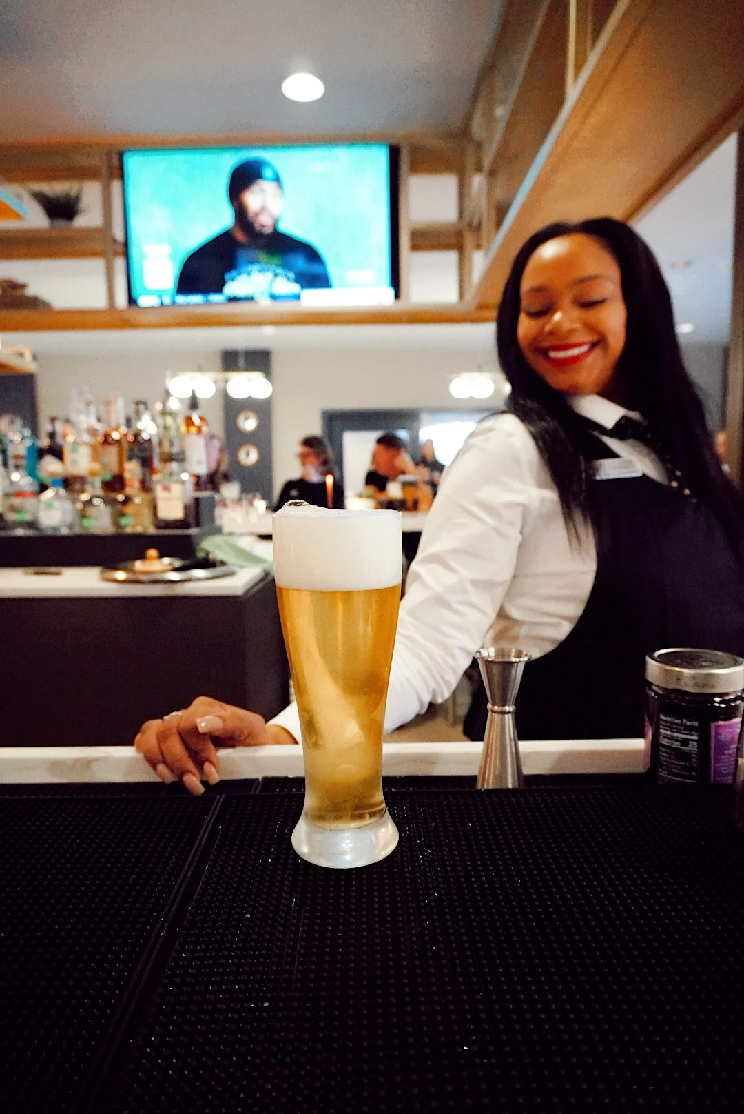 Bartender serving a freshly poured beer at the bar inside Side Eye restaurant at The Mecklen Hotel in Charlotte.