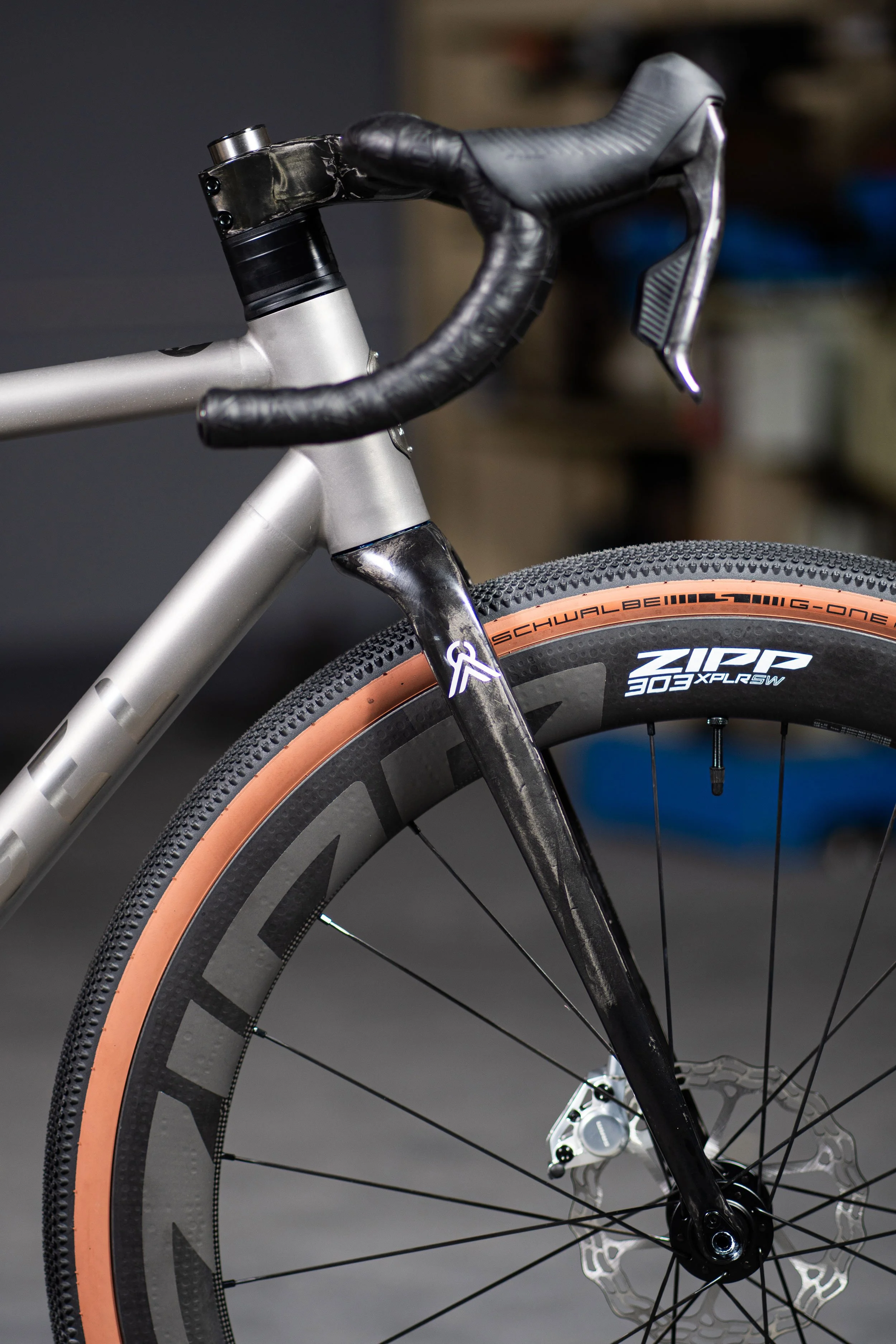 Close-up of a modern bicycle's front section, showing the handlebar, fork, and wheel with a tire labeled 'Schwalbe' and 'Zip 300 XPLRSW'.