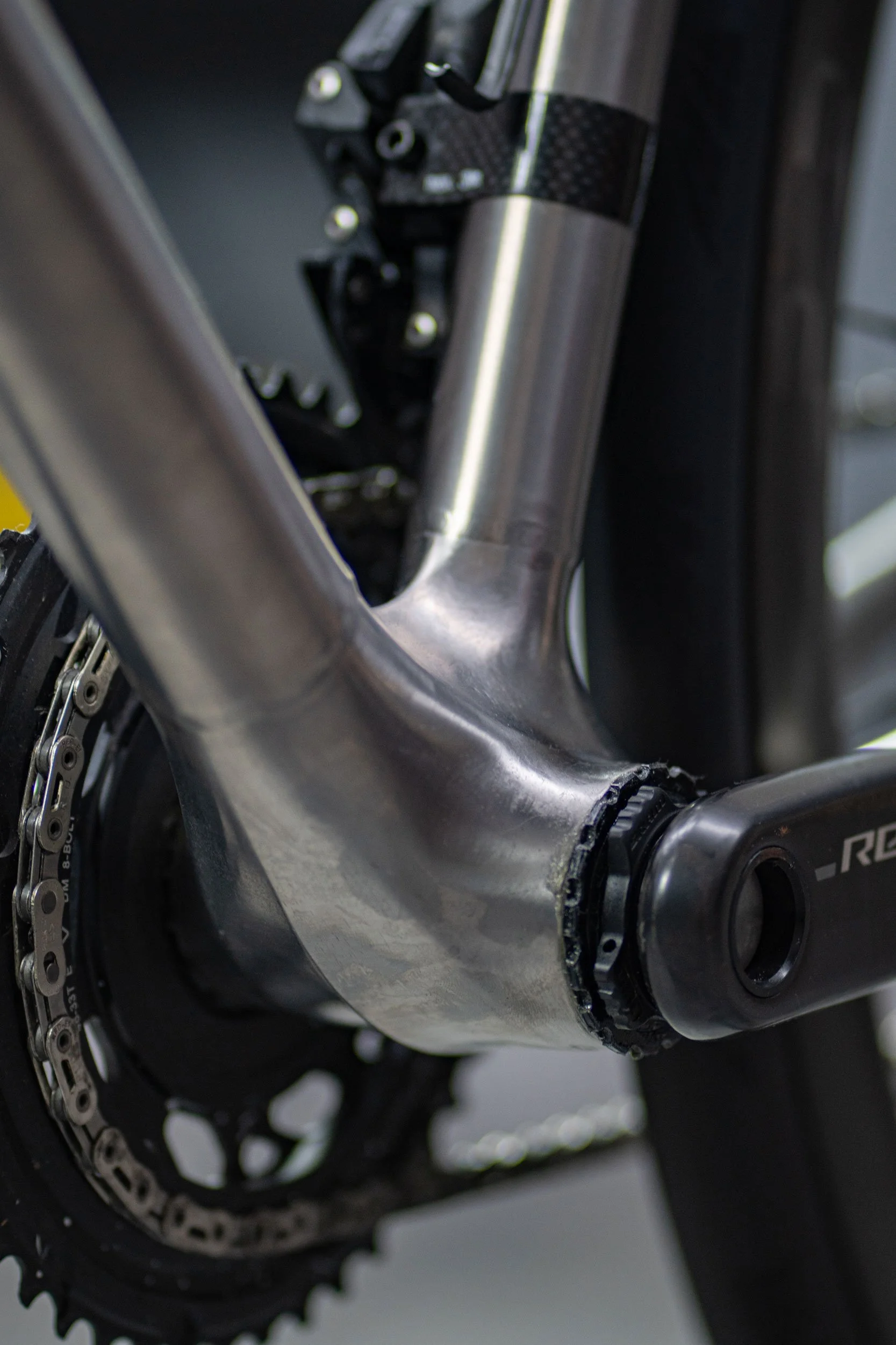 Close-up of a bicycle's bottom bracket area with a carbon fiber fork and chainring, highlighting the bike's high-performance components.