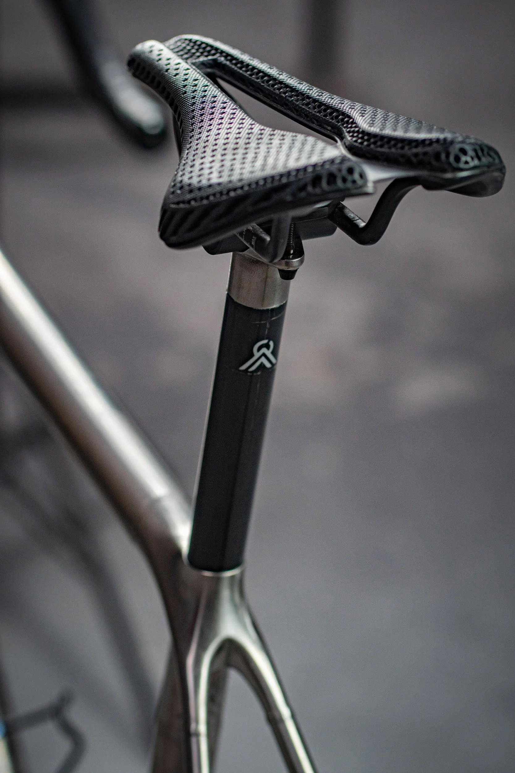 Close-up of a bicycle saddle and seat post, with part of the bike frame visible in the background.