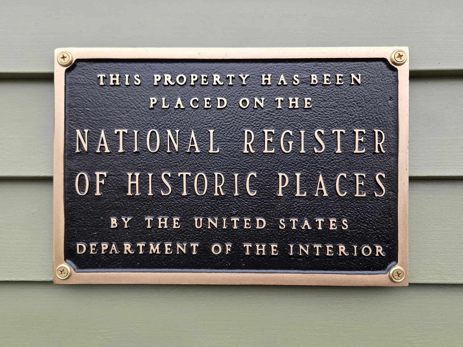 A plaque mounted to the exterior of the building describing that the property is on the National Register of Historic Places