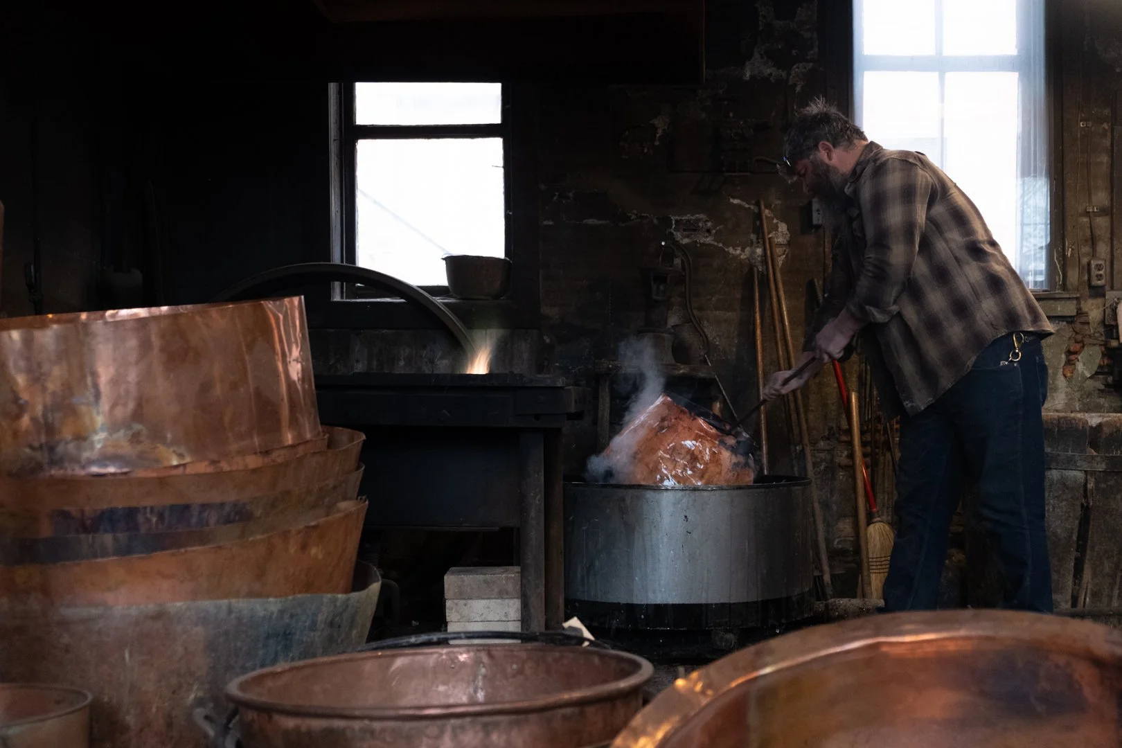 A man working with molten metal in a blacksmithing workshop.