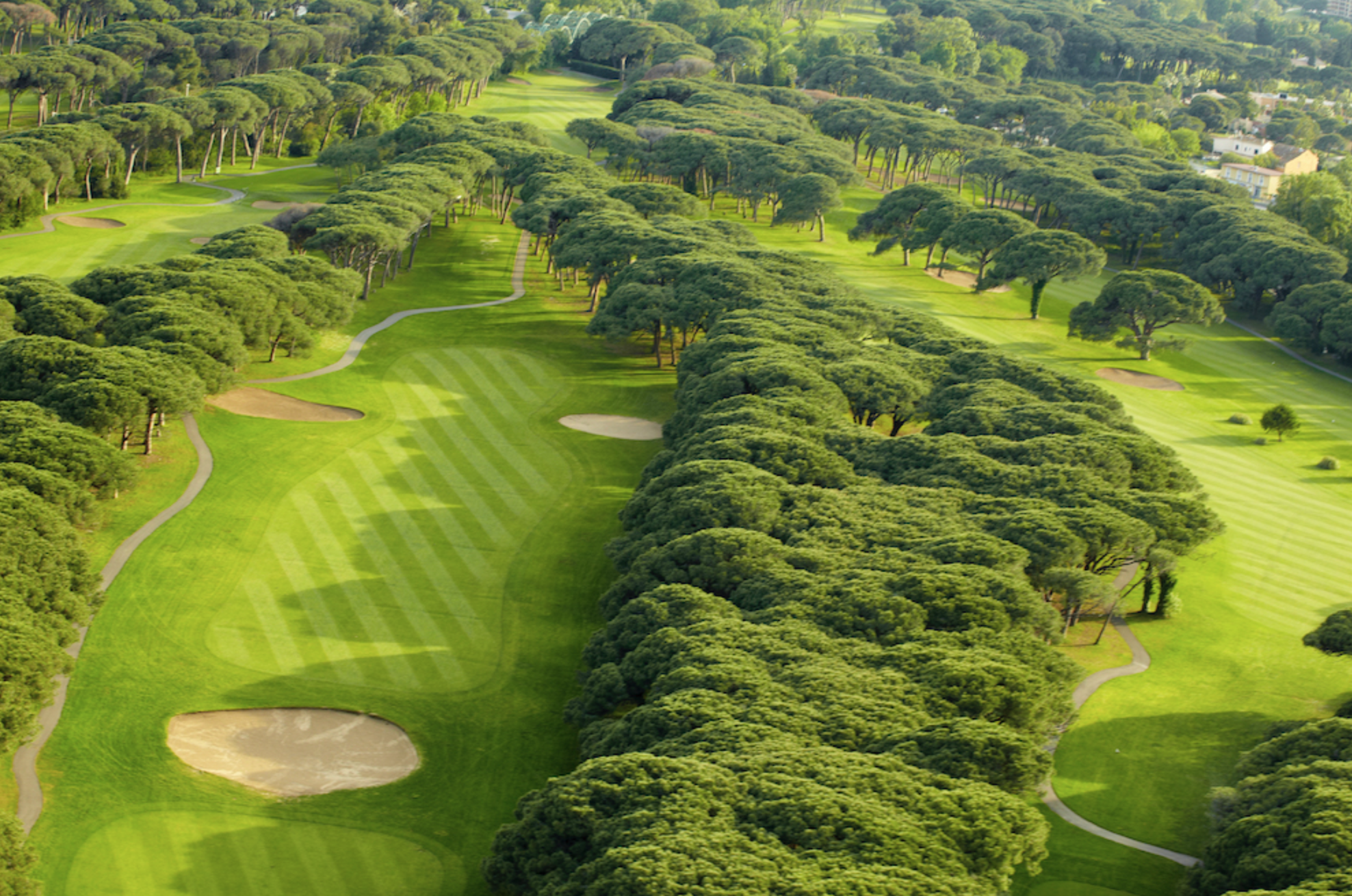 Aerial view of a golf course with multiple sand traps, fairways, green areas, and trees.