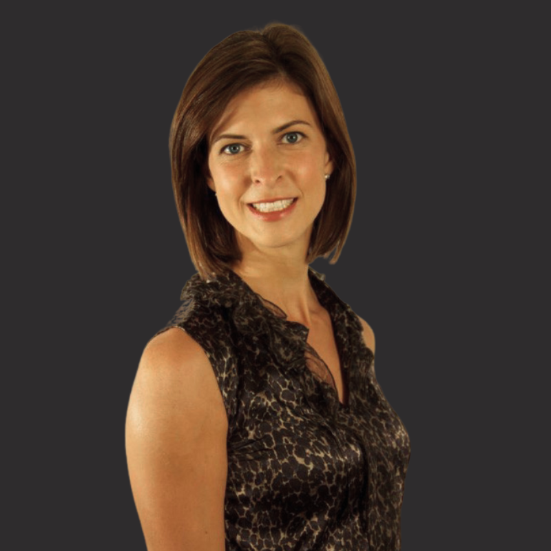 A woman with shoulder-length brown hair wearing a sleeveless leopard print top standing against a dark gray background.