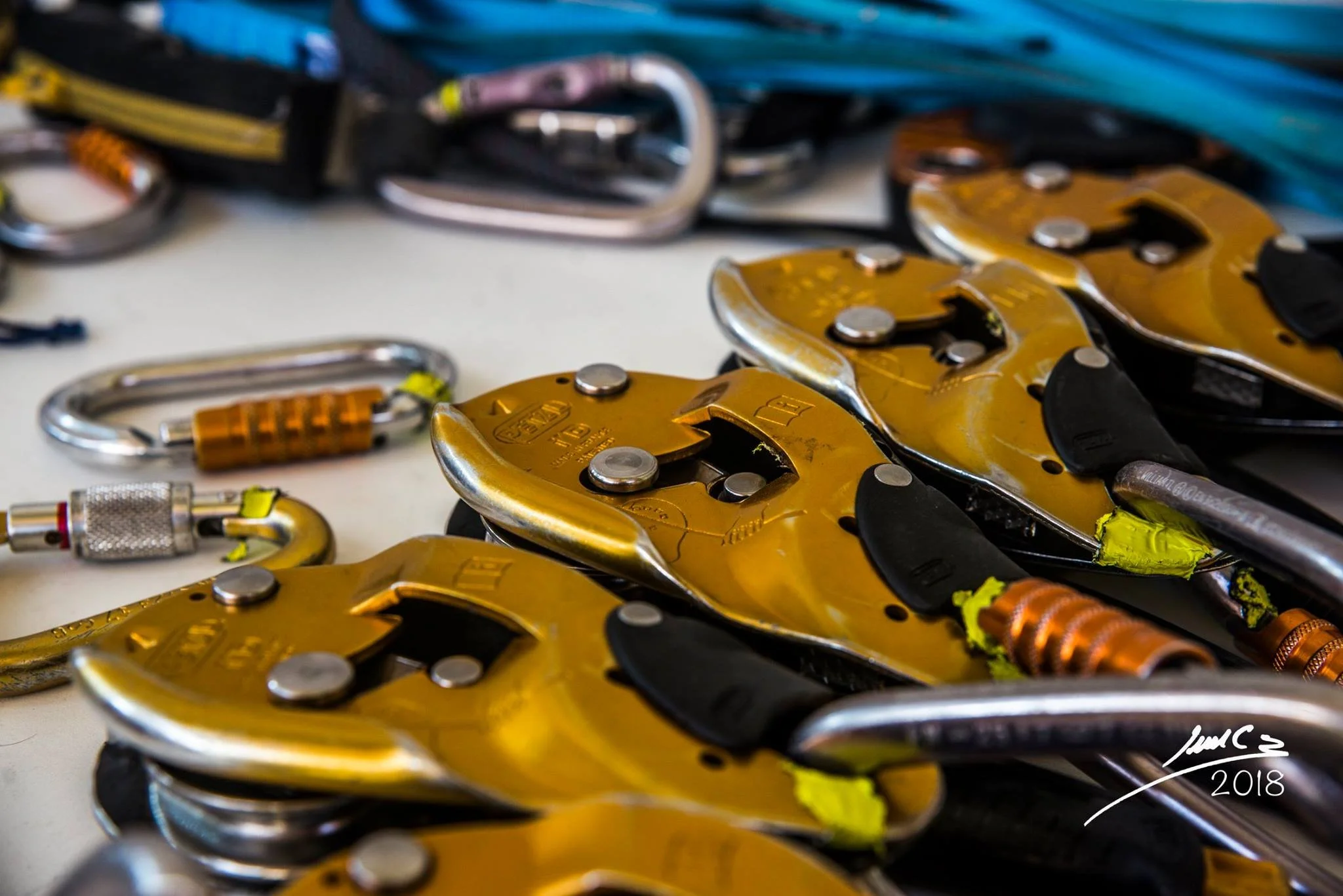 Conjunto de arneses y anclajes de escalada en color amarillo, colocados sobre una mesa.
