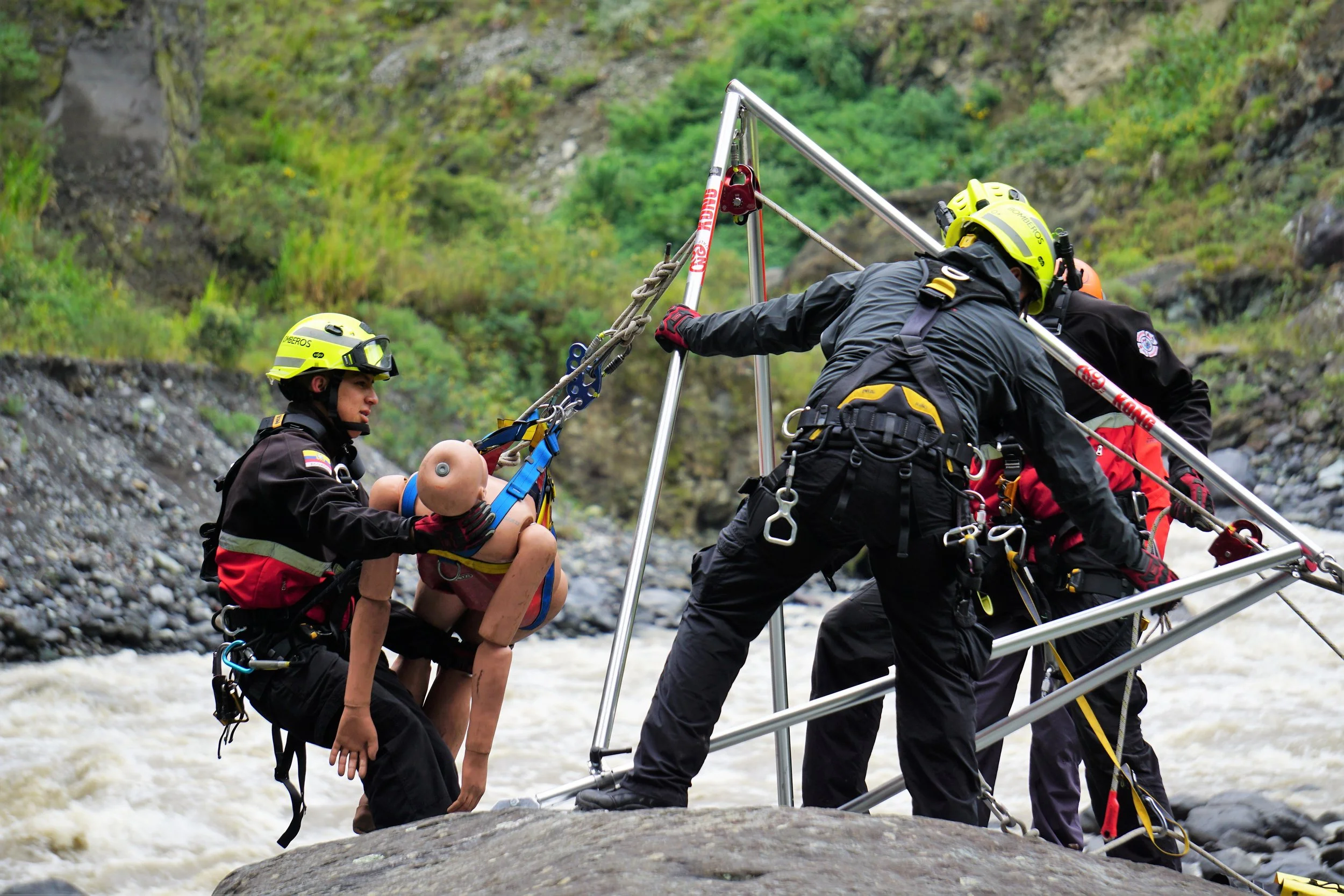 Rescatistas ayudando a una persona con lesiones en un entorno de río, utilizando equipo de seguridad y una camilla de rescate.