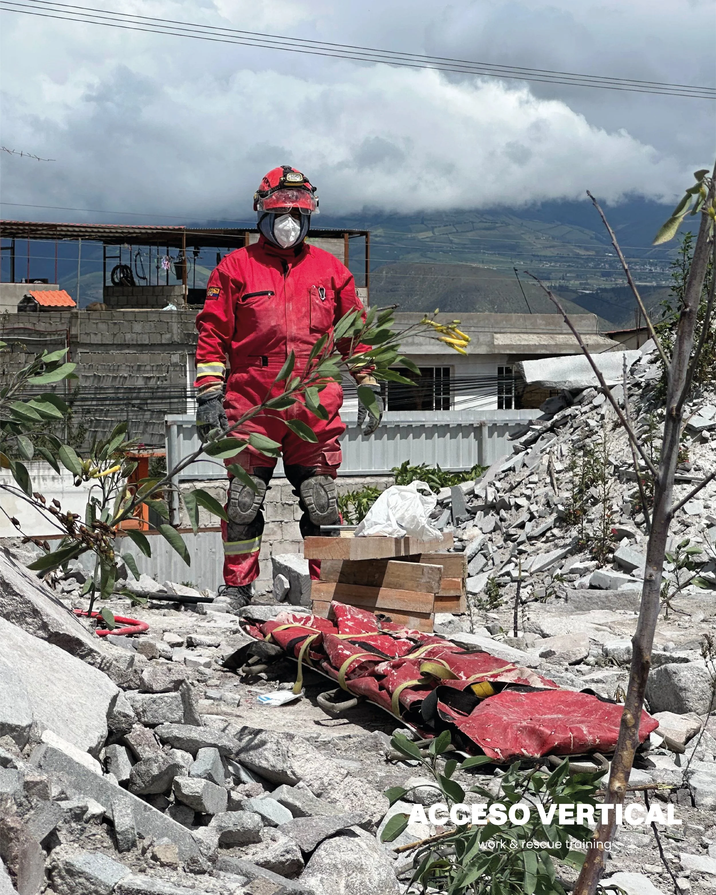 Persona en equipo de rescate en un área de desastre con escombros y una camilla de rescate en el suelo.