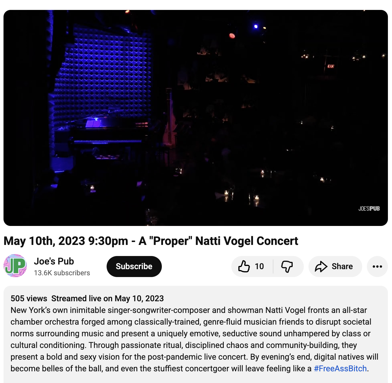 A dark stage with a blue-lit piano and textured wall in the background, set up for a jazz concert at Joe's Pub. Screenshot of Joe's Pub YouTube page.