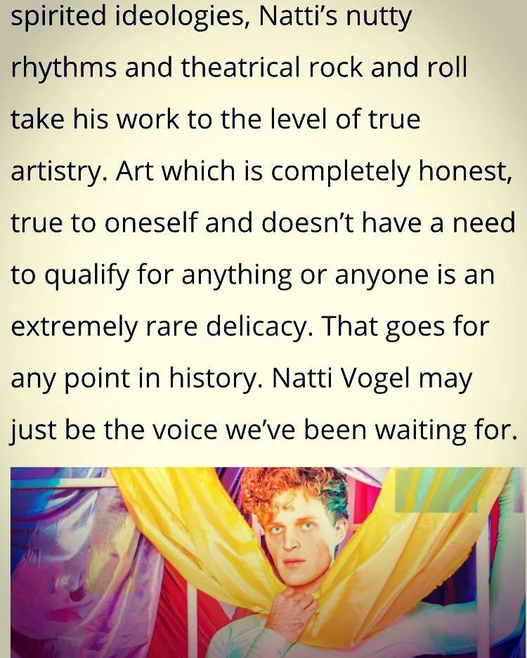 Natti Vogel surrounded by colorful fabric drapes, with a serious expression on his face.